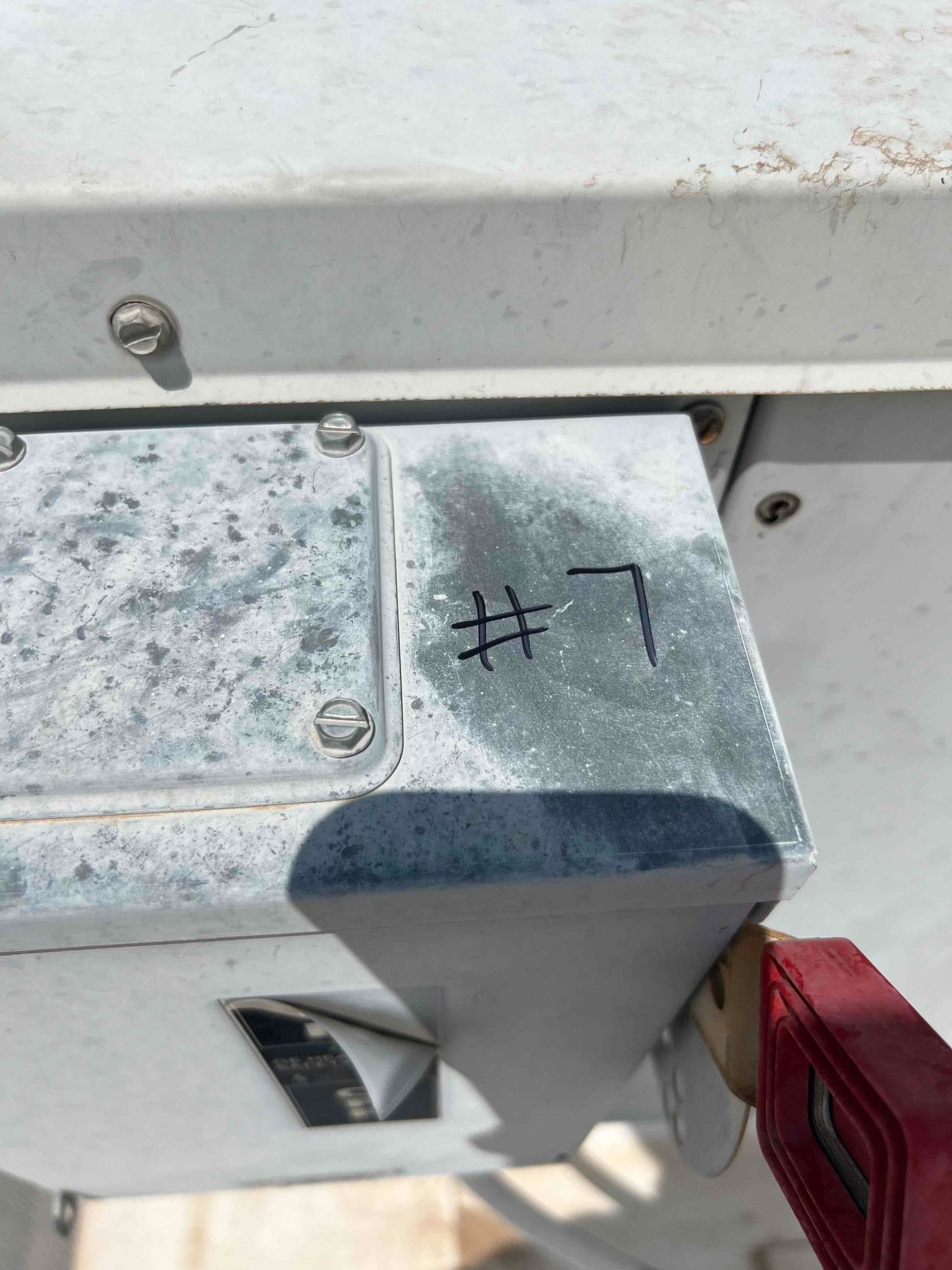 Surface-mount electrical box on the outdoor unit, labeled "#7," with weathered finish and red disconnect handle visible.