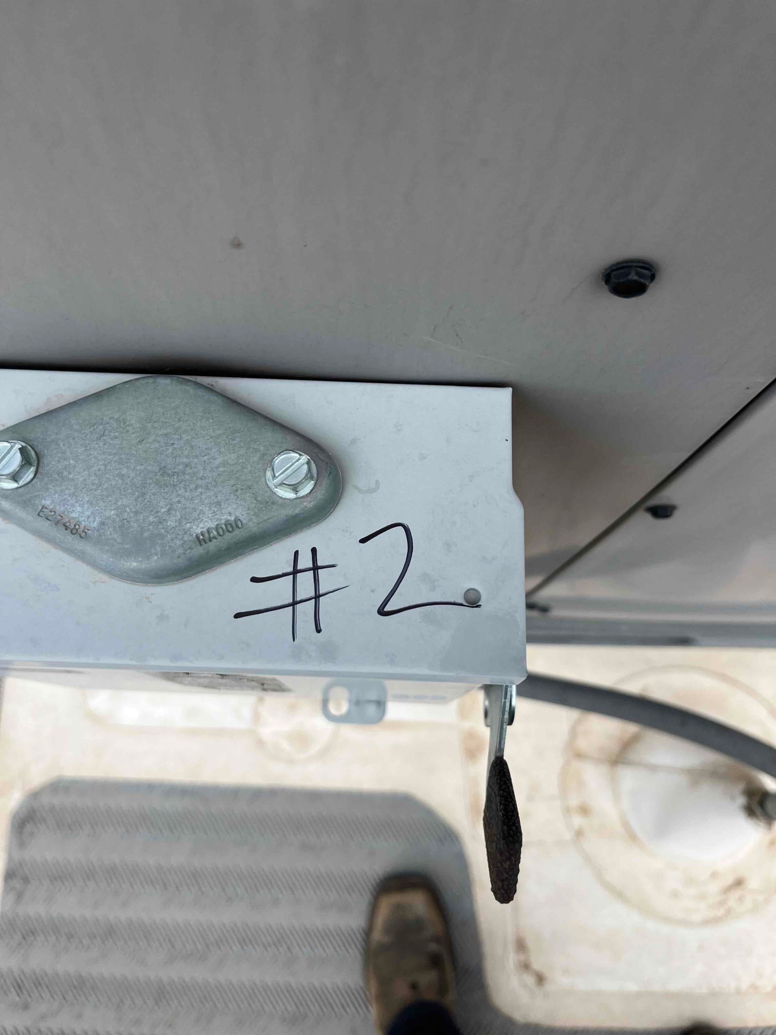 Surface-mount electrical box secured with two screws, marked '#2', installed near HVAC equipment with visible conduit.