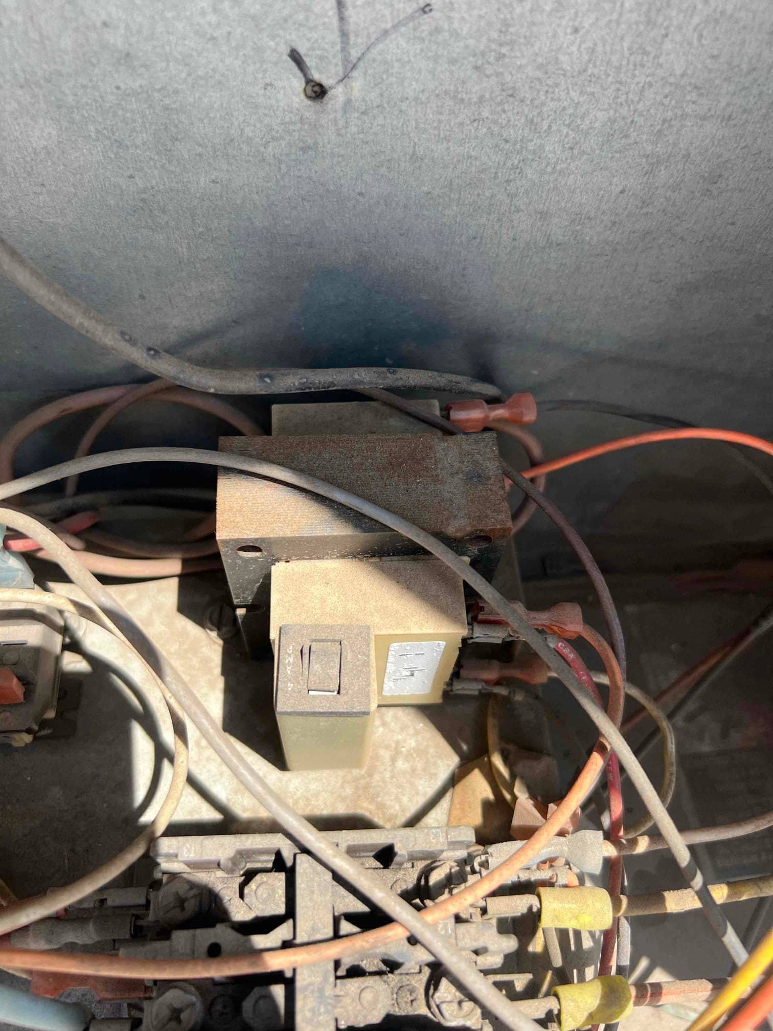 Surface-mount low-voltage transformer installed inside the condenser control compartment, with connected low-voltage wiring and wire nuts visible.