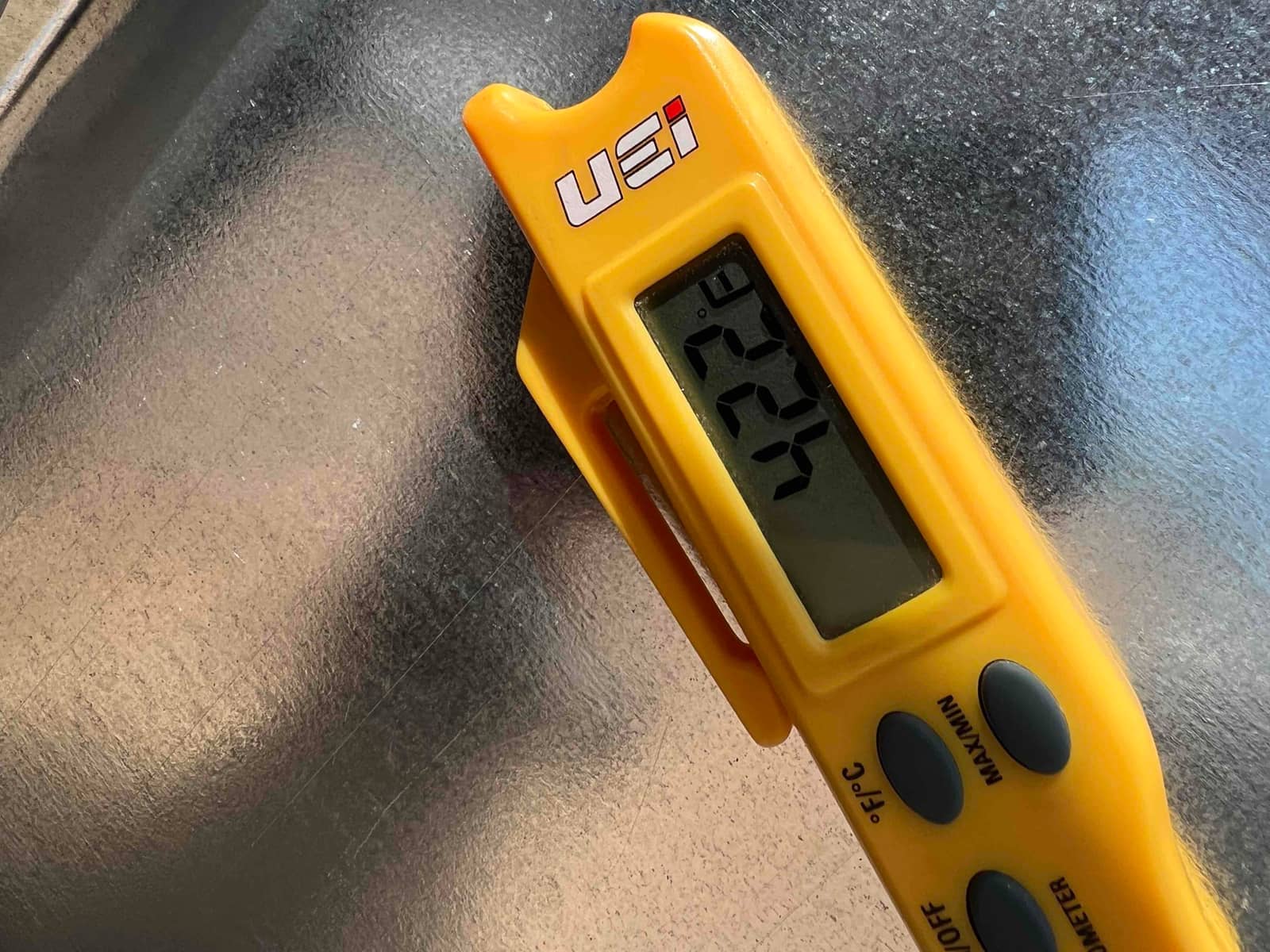 Digital thermometer shows 42.2 degrees Fahrenheit while checking air temperature on a galvanized HVAC surface.