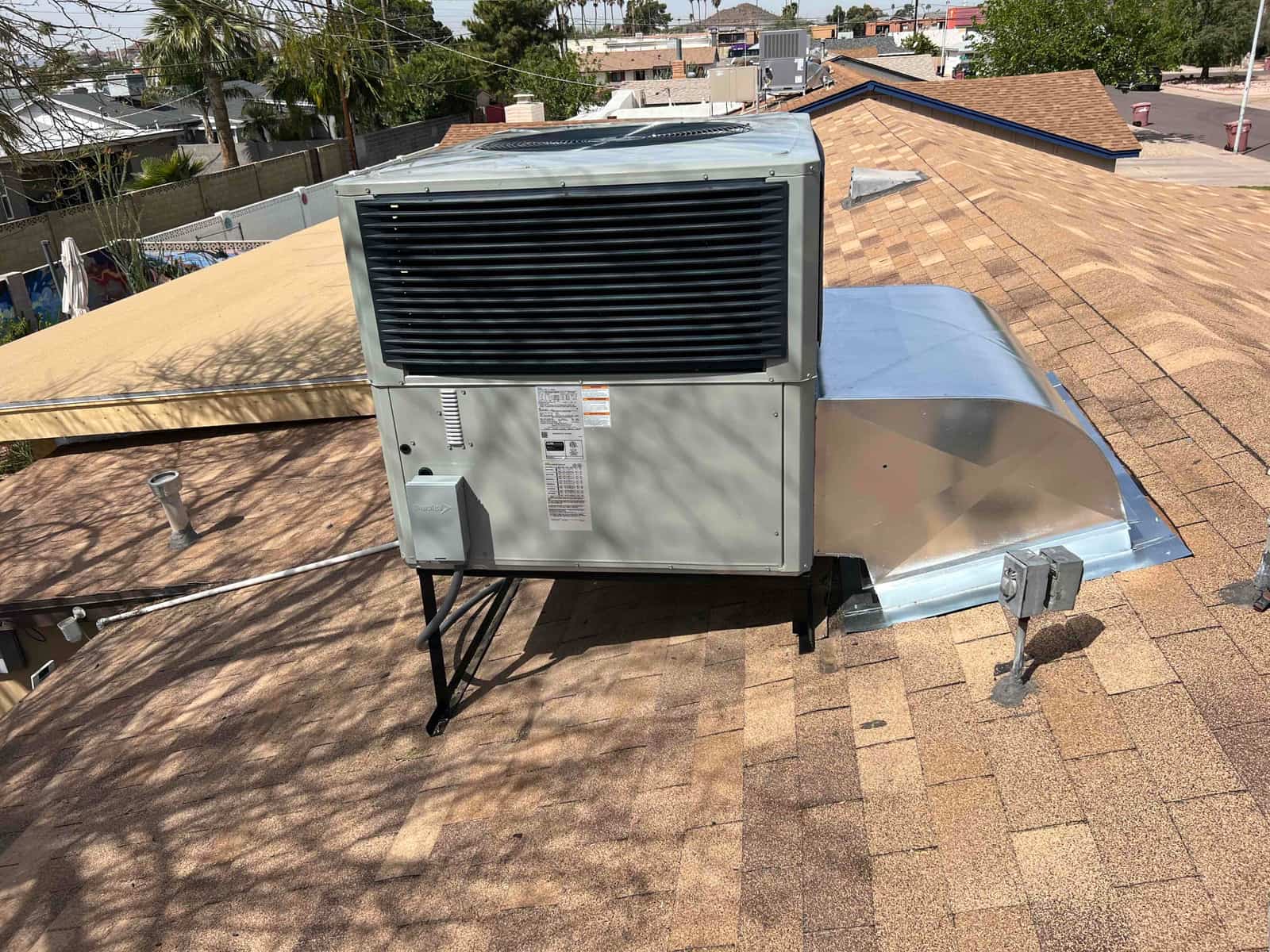 New rooftop packaged HVAC unit installed on stand with sealed curb adapter and rooftop disconnect visible.