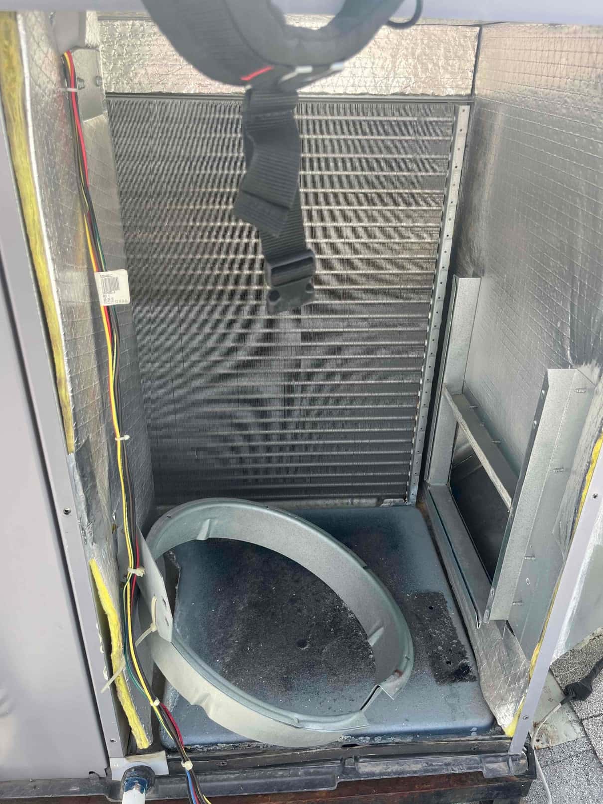 Air handler cabinet open with evaporator coil visible and blower housing ring removed from the bottom compartment.