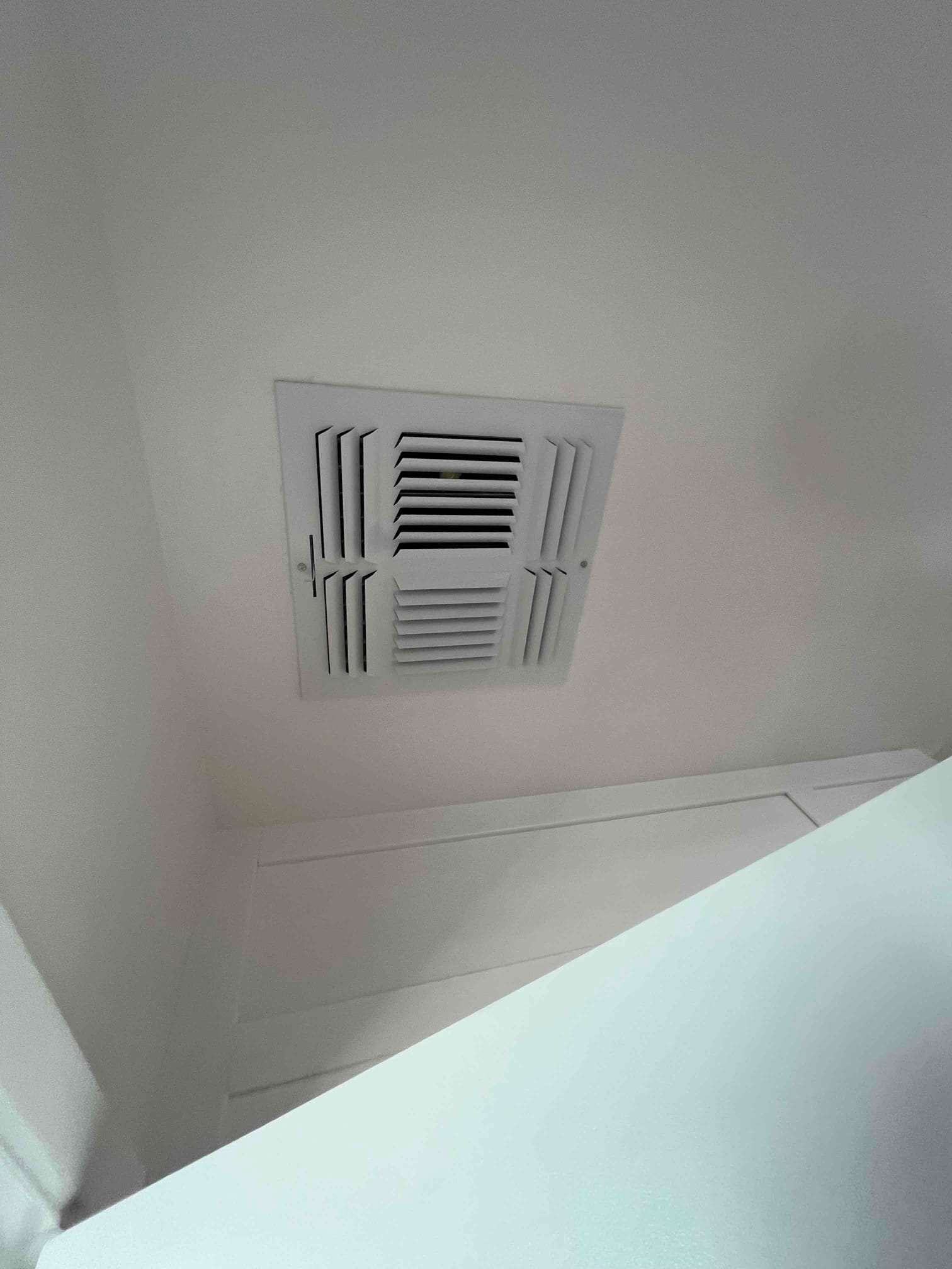 Ceiling supply register installed flush with finished surface, showing clean grille and secured mounting screws.