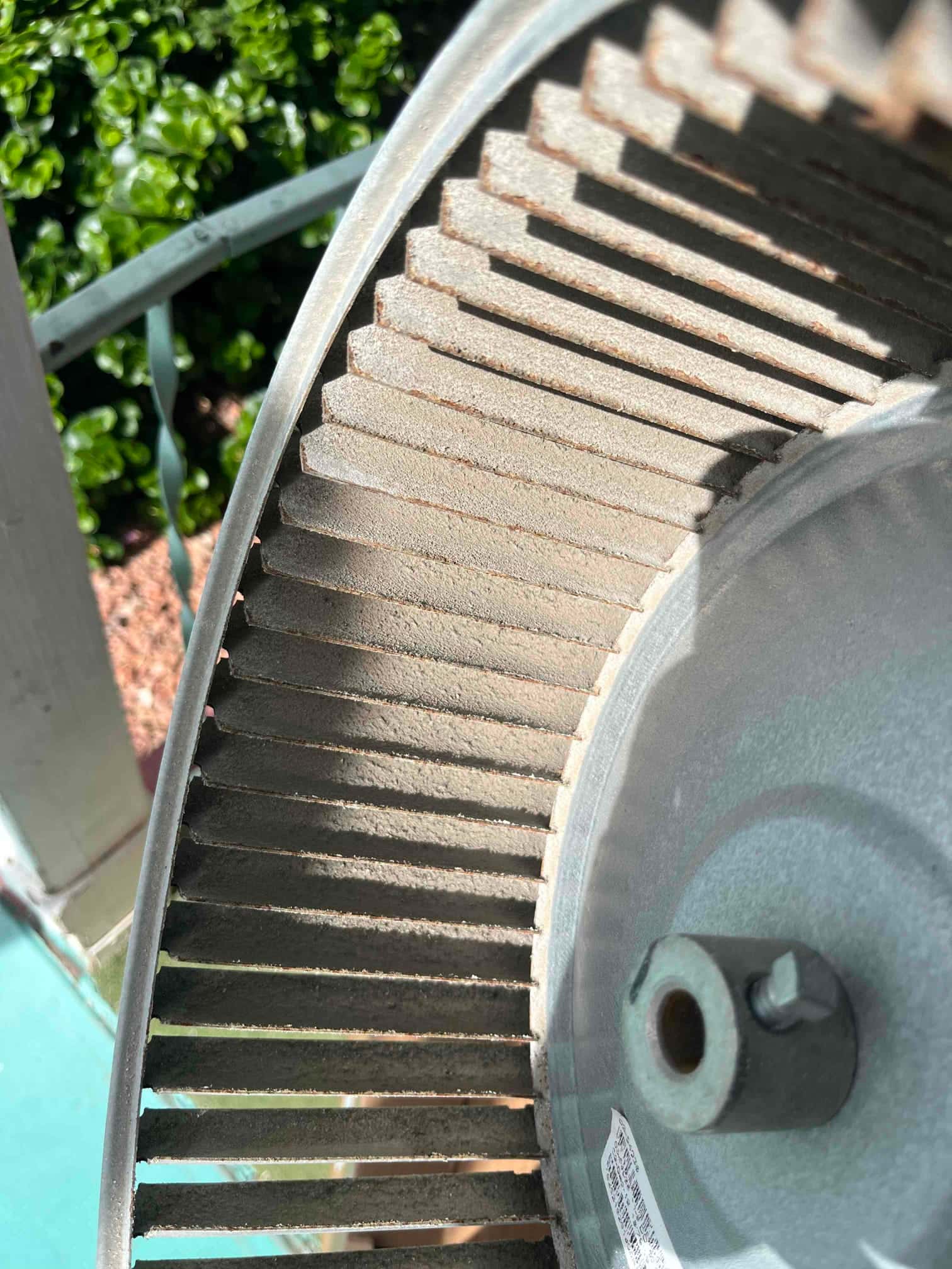 Close-up of a dusty blower wheel removed from an HVAC system, showing buildup on the blades and hub.