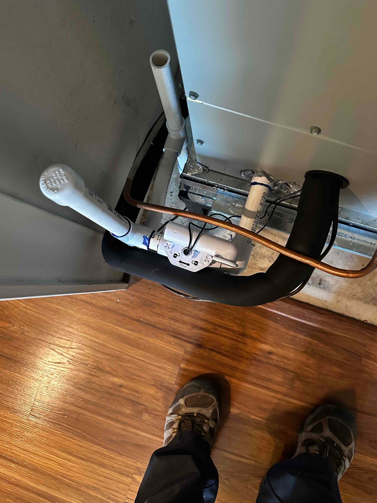 Condensate drain piping and insulated refrigerant line connected to the indoor unit, with clean floor and secure penetrations visible.