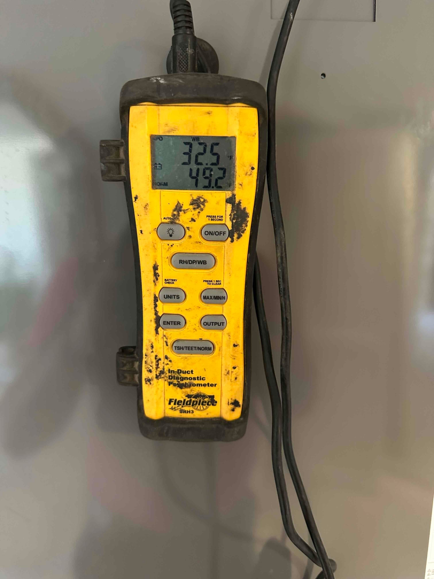 Digital in-duct psychrometer shows readings on the display during air temperature and humidity checks at the air handler.