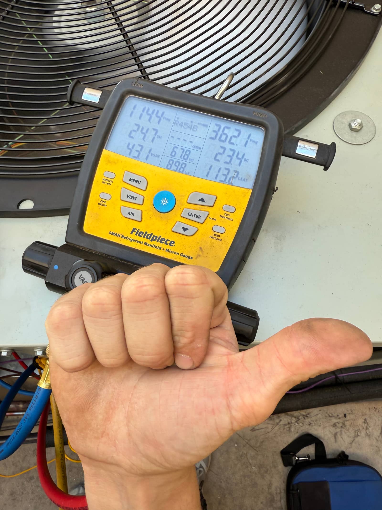 Digital manifold attached to the outdoor unit shows system operating pressures with separate high and low readings during commissioning.
