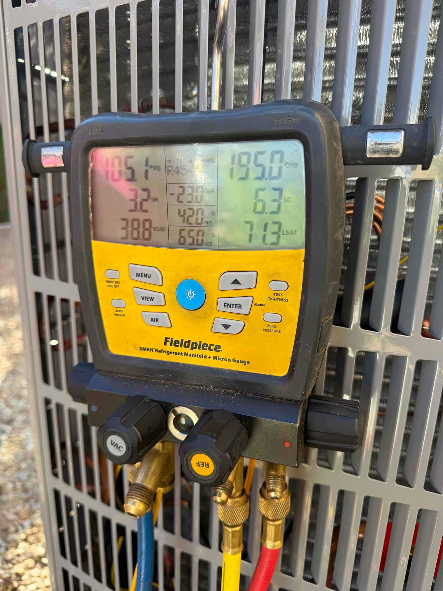 Digital manifold connected at the outdoor unit shows operating pressures and calculations during system commissioning.