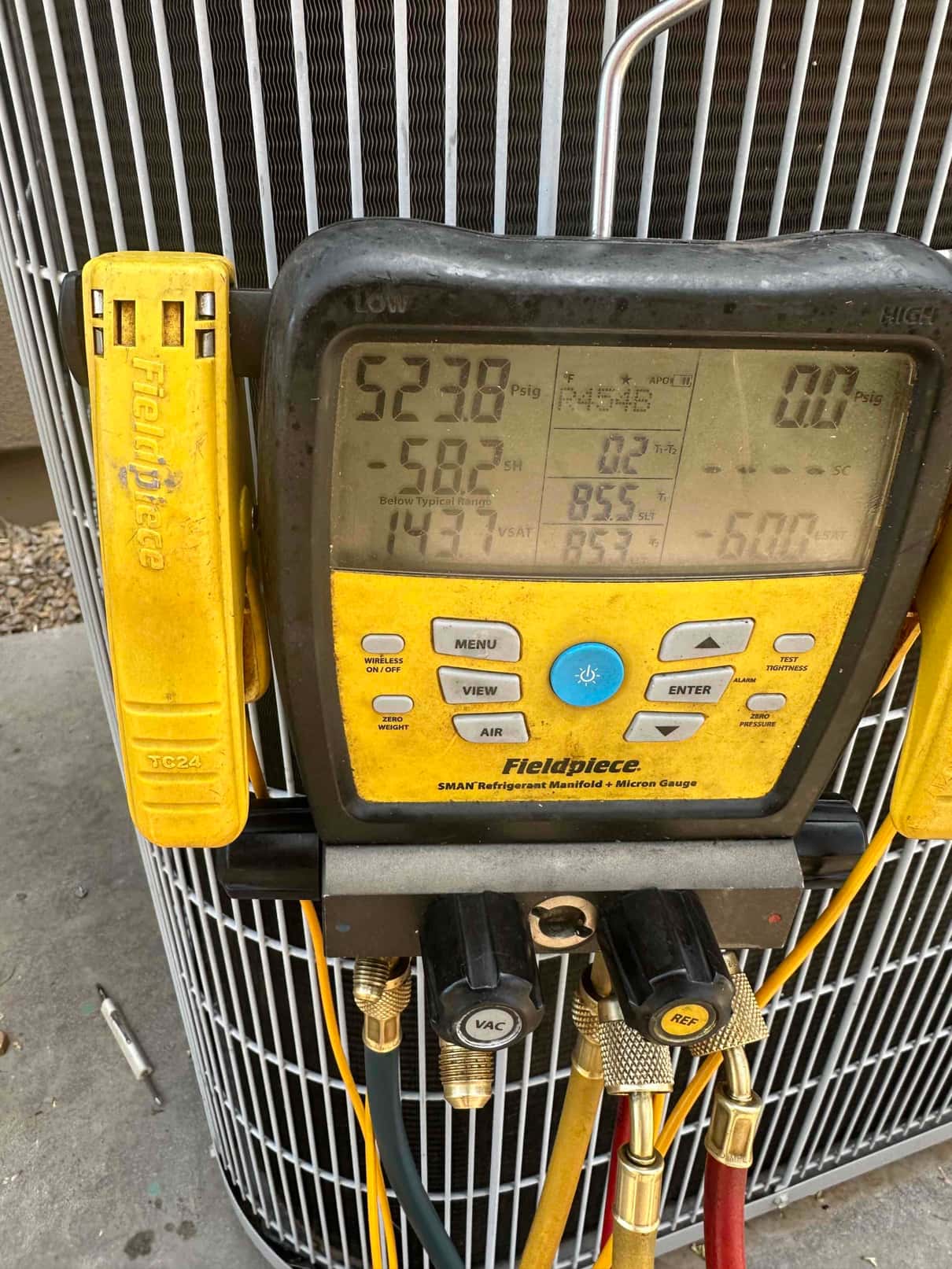 Digital manifold on the outdoor unit shows operating pressures with hoses connected for system commissioning.