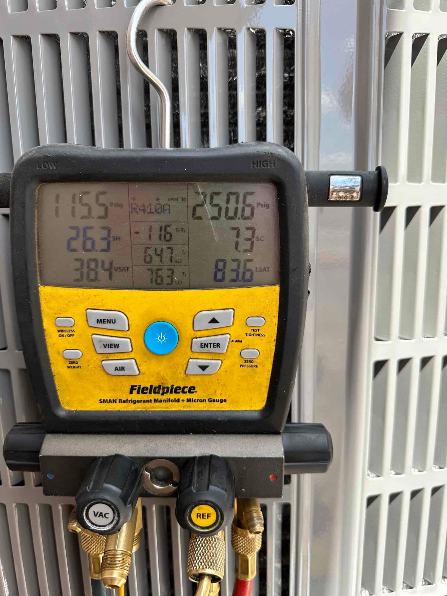 Digital manifold on the outdoor unit shows operating pressures with refrigerant, documenting system commissioning readings during startup.