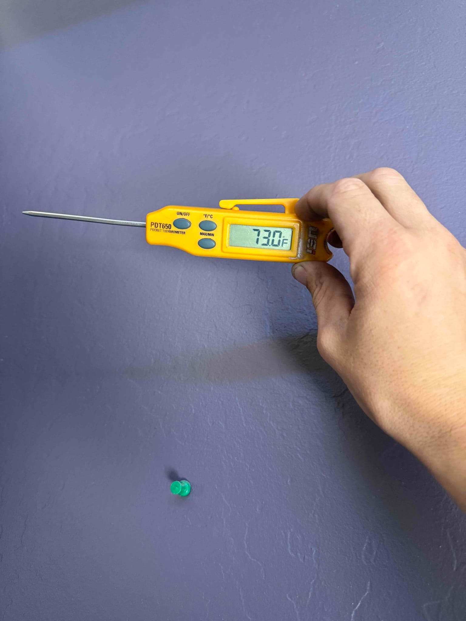 Digital probe thermometer shows 73.0°F while measuring room air during HVAC return air temperature check.