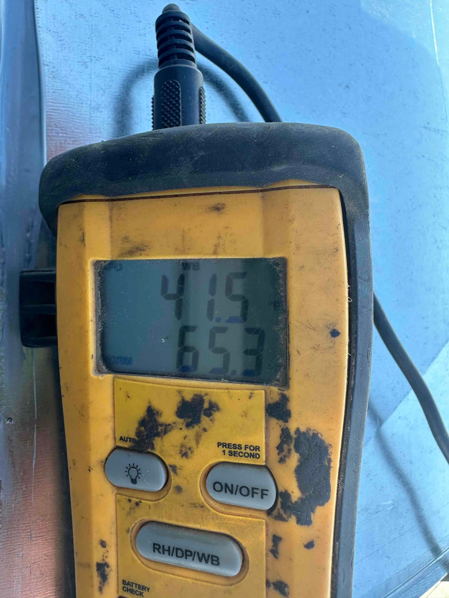 Digital thermometer displays 41.5 and 65.3 degrees while checking air temperatures during HVAC commissioning.
