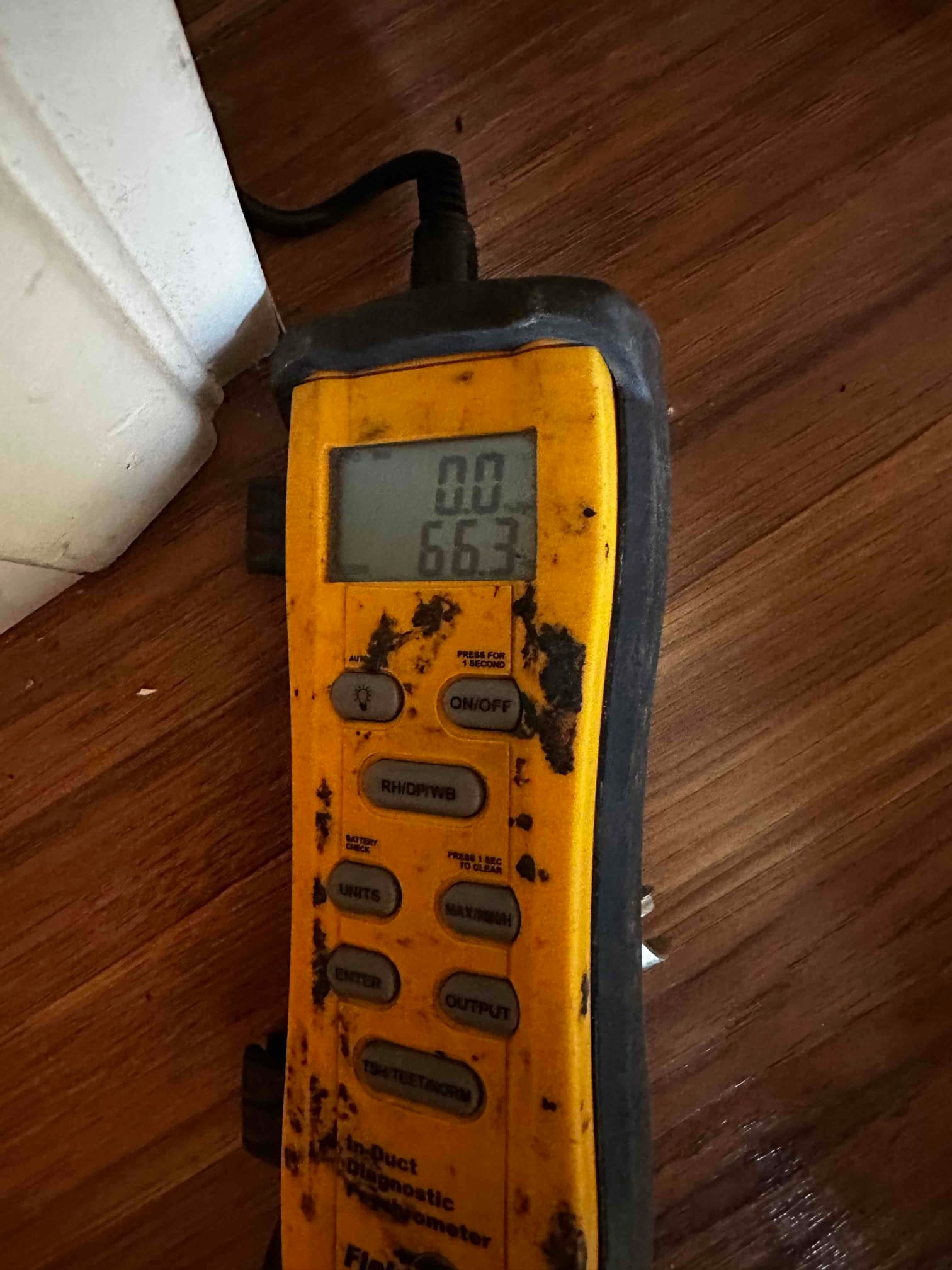 Digital thermometer on the floor shows an air temperature reading of 66.3 degrees Fahrenheit during commissioning checks.