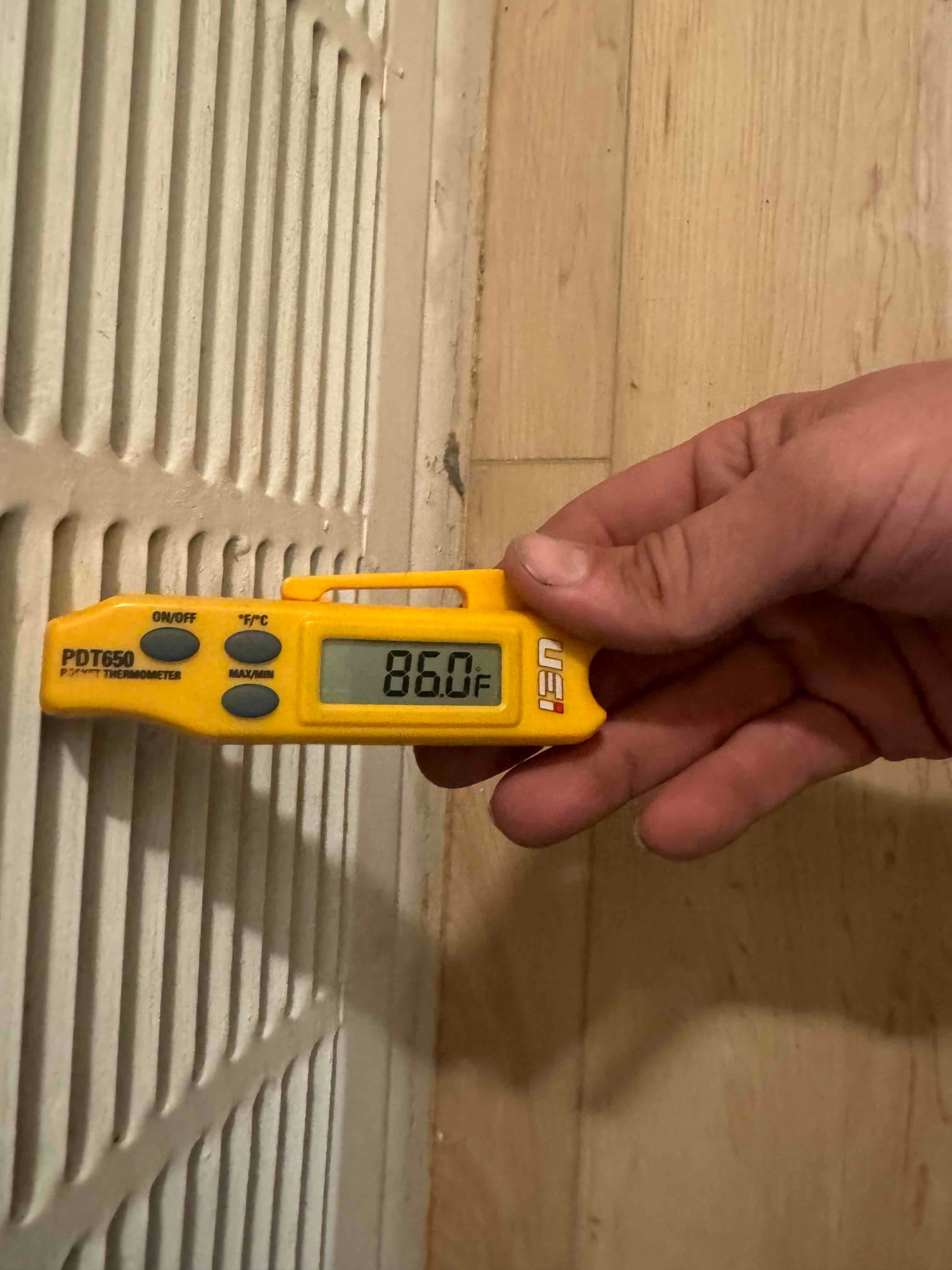 Digital thermometer at a return grille reads 86.0°F during air-side commissioning of the new system.