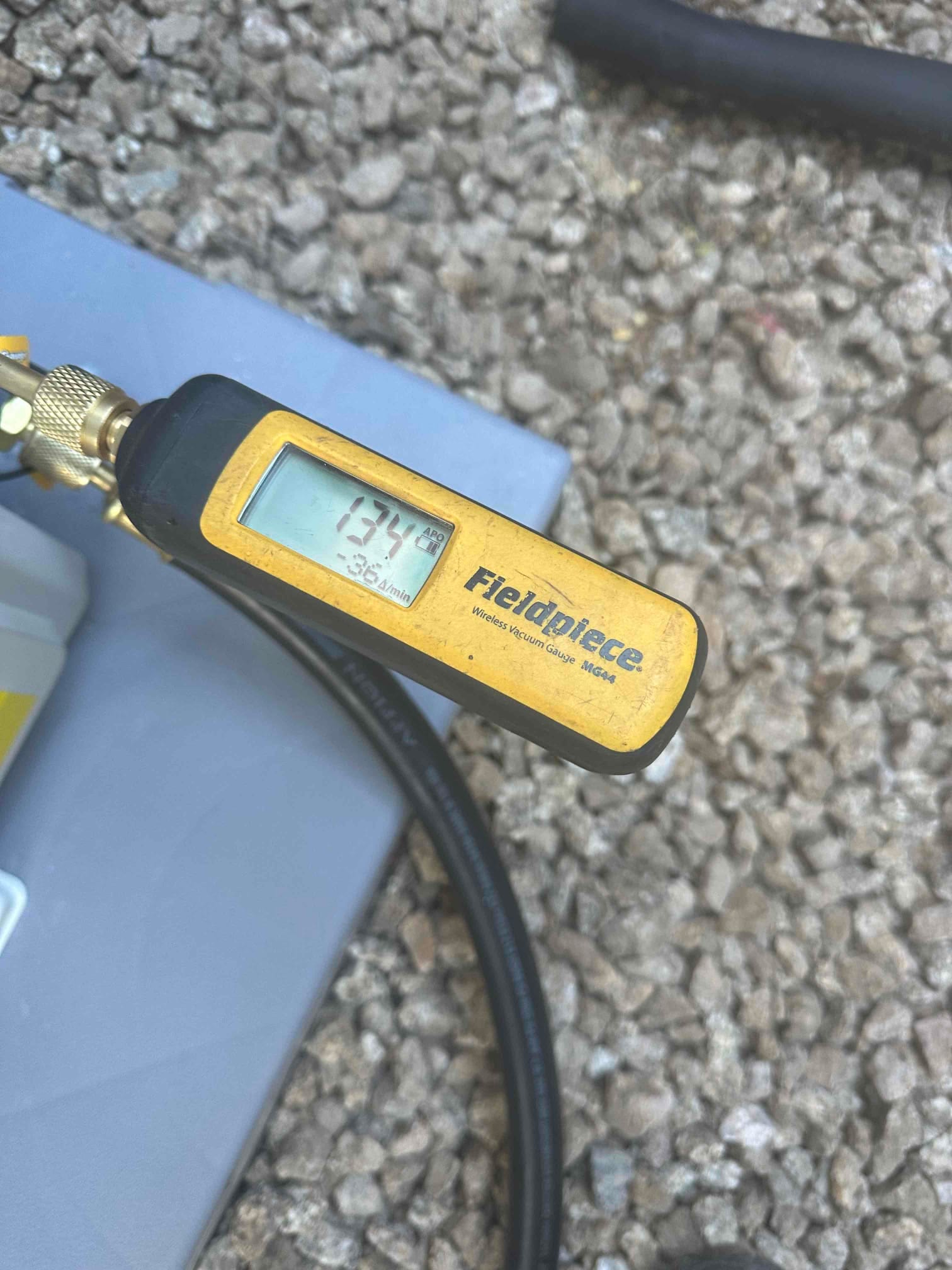 Digital vacuum gauge connected to the system reads 134 microns, confirming a deep evacuation before charging refrigerant.