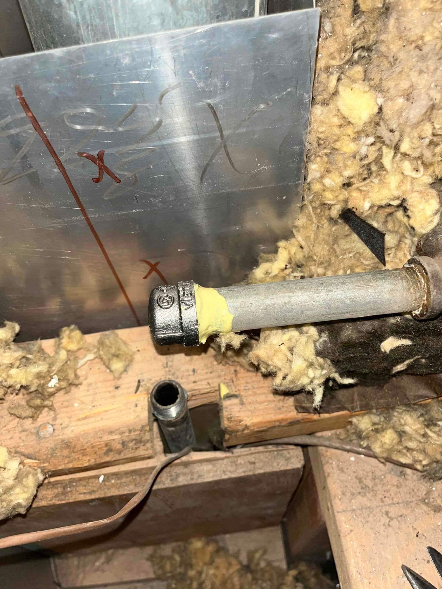 Gas piping and fittings routed through framing near ductwork and insulation during HVAC installation preparation.