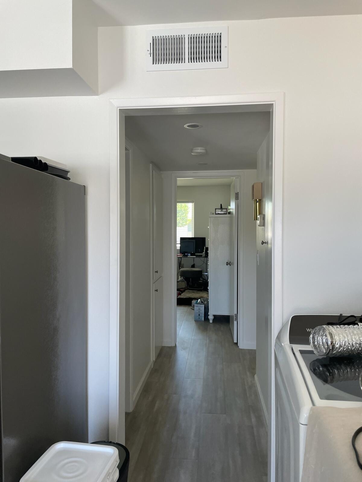 Hallway return air grille installed above the doorway, showing finished interior placement near kitchen and laundry appliances.