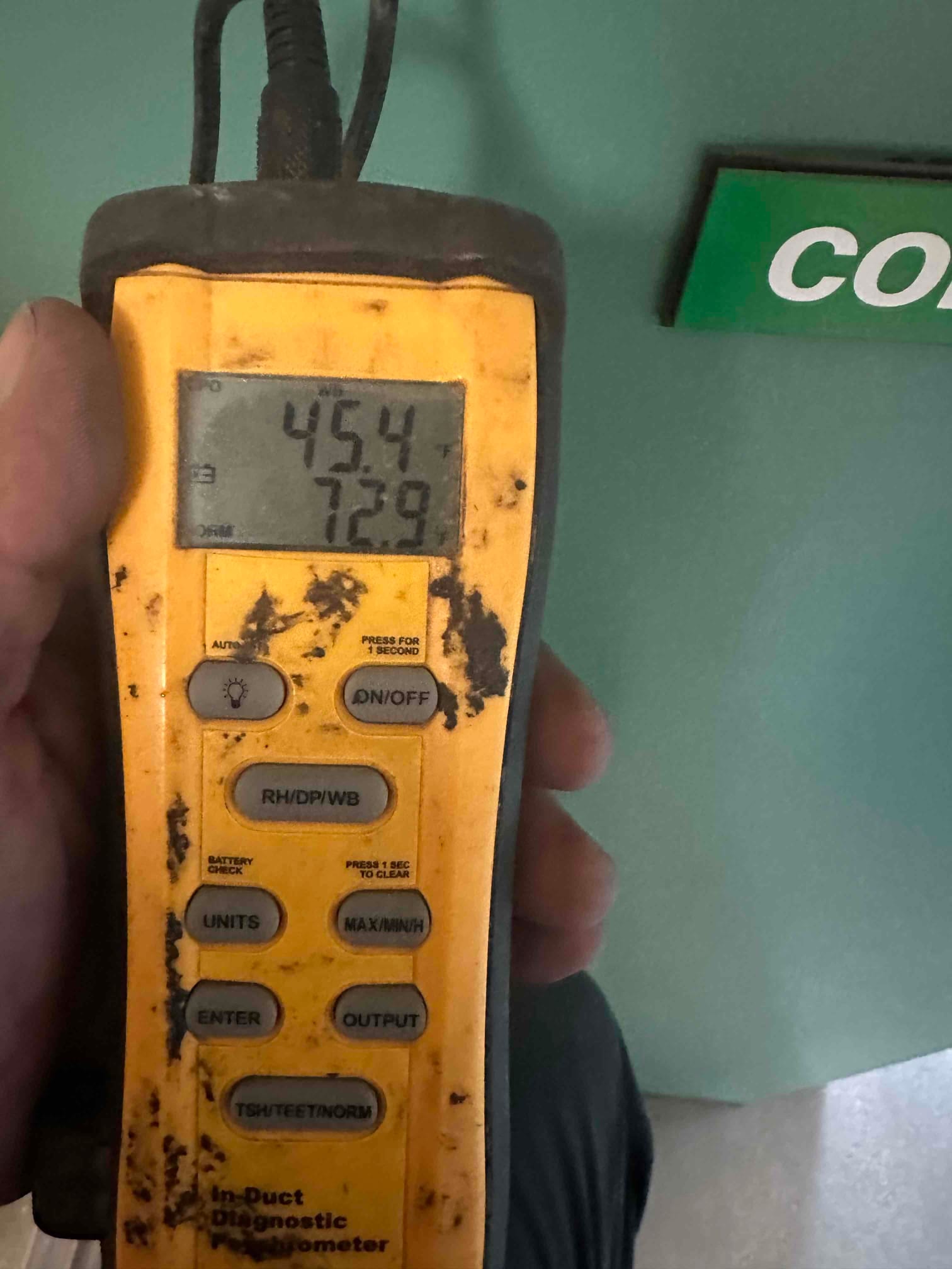 Handheld digital thermometer displays 45.4°F and 72.9°F during air temperature checks at the HVAC system.