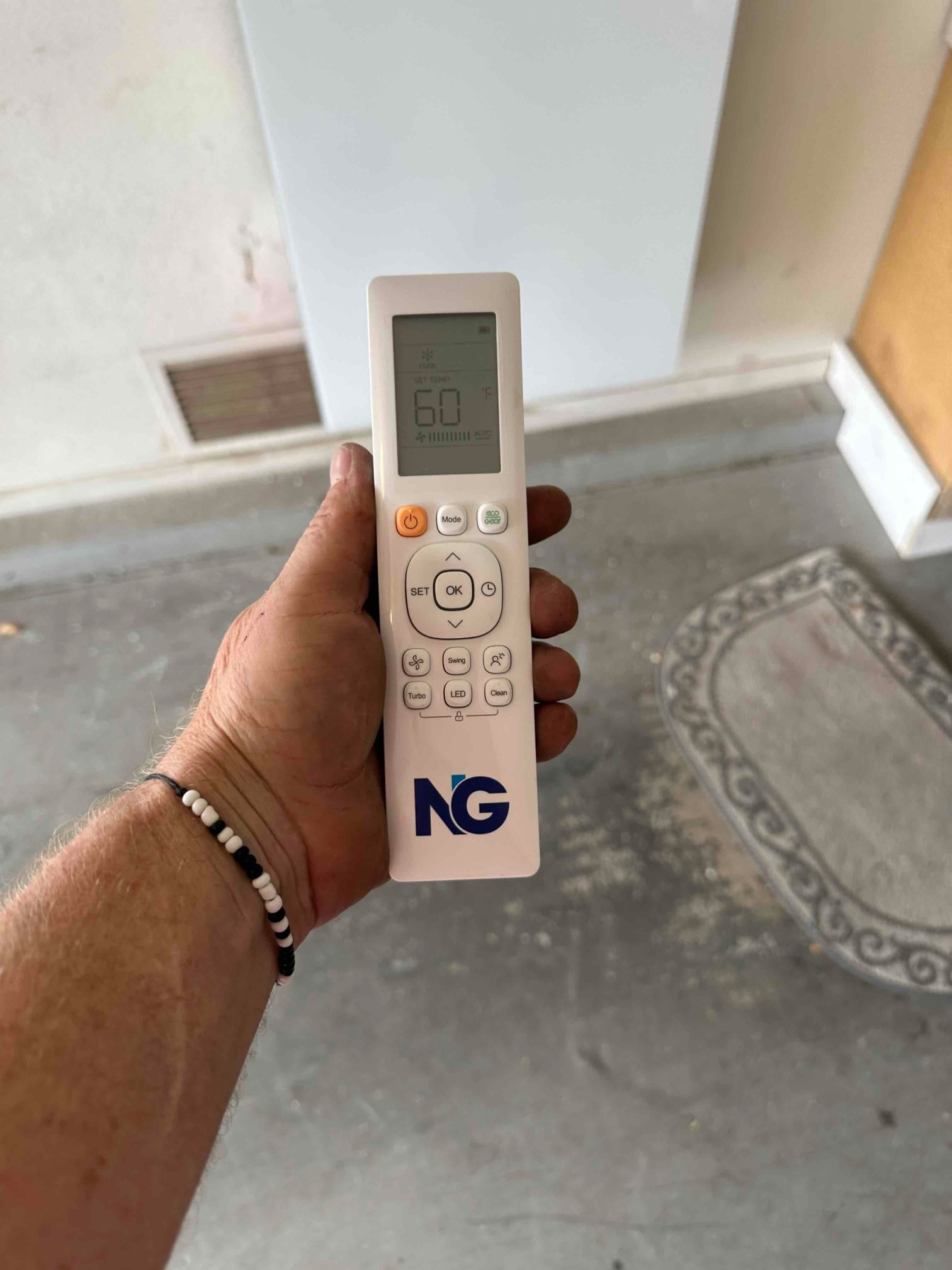 Handheld HVAC remote control set to 60°F cooling mode, shown during system startup in the installation area.