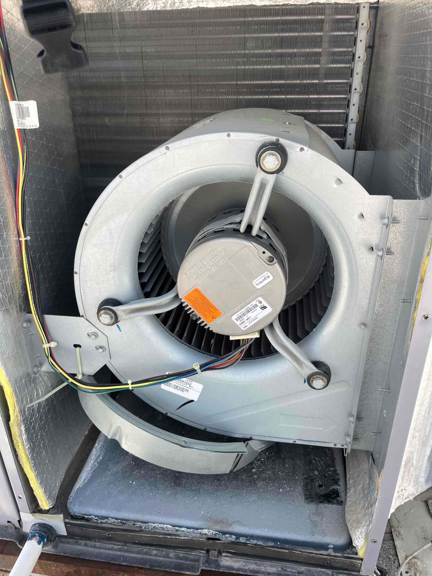 Indoor blower assembly exposed inside the air handler, showing clean blower wheel, motor housing, and wiring connections.