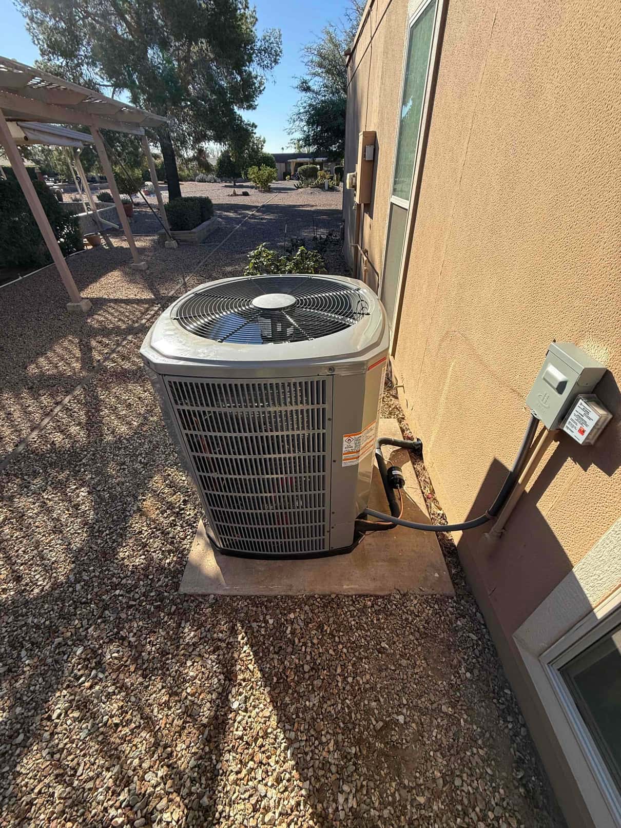 New outdoor heat pump condenser set on a level pad with insulated line set and weatherproof disconnect installed.
