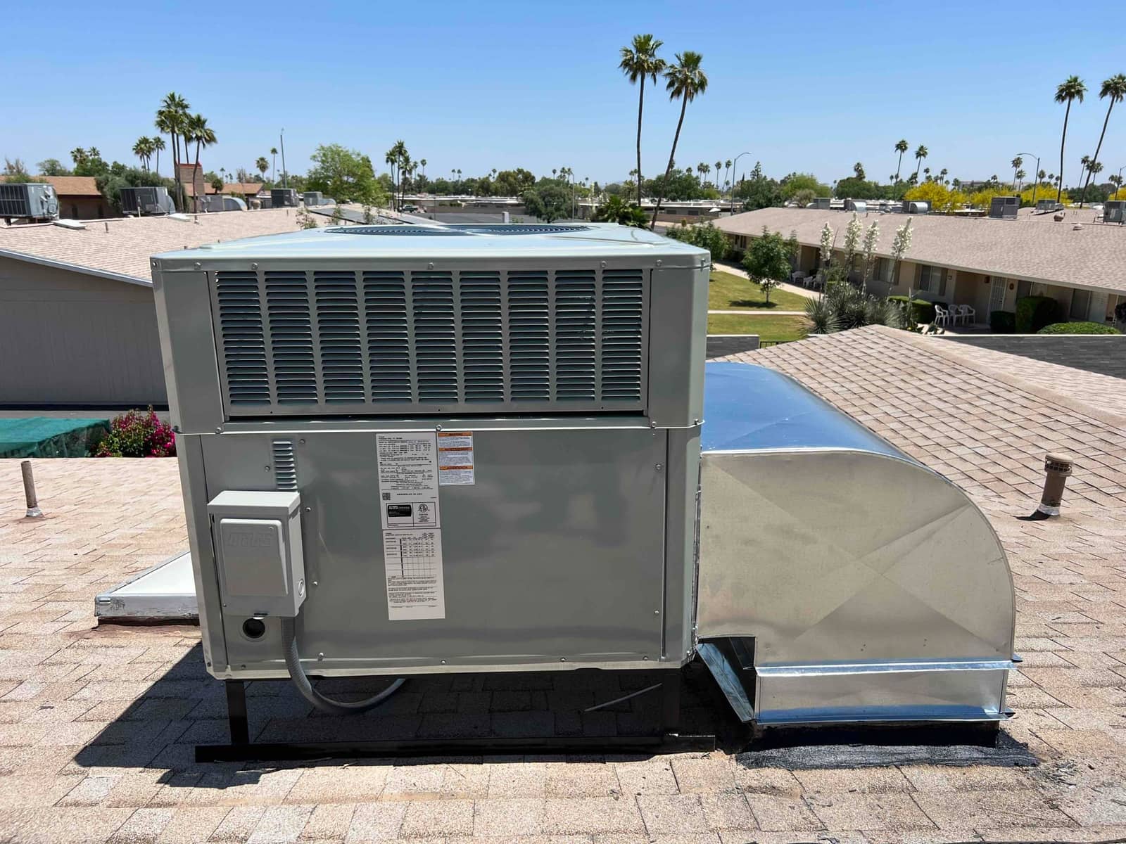 New rooftop package unit mounted on a stand with sealed supply/return duct curb and exterior electrical disconnect.