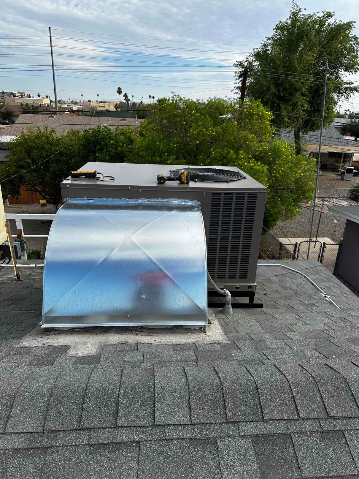 New rooftop package unit set on curb with sealed sheet-metal transition and electrical whip routed to the disconnect.