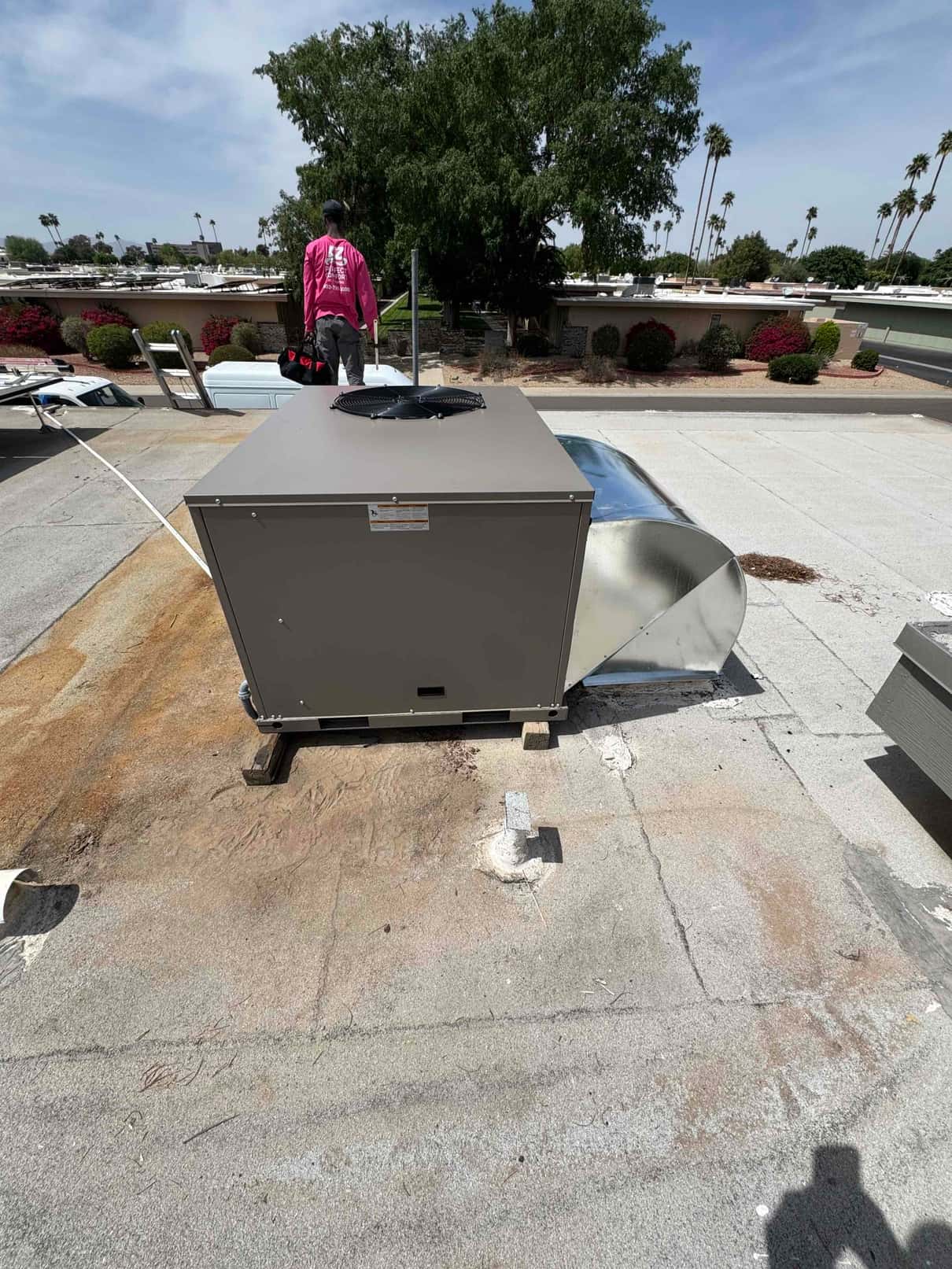 New rooftop package unit set in place on curb with transition ductwork installed, ready for final connections and commissioning.