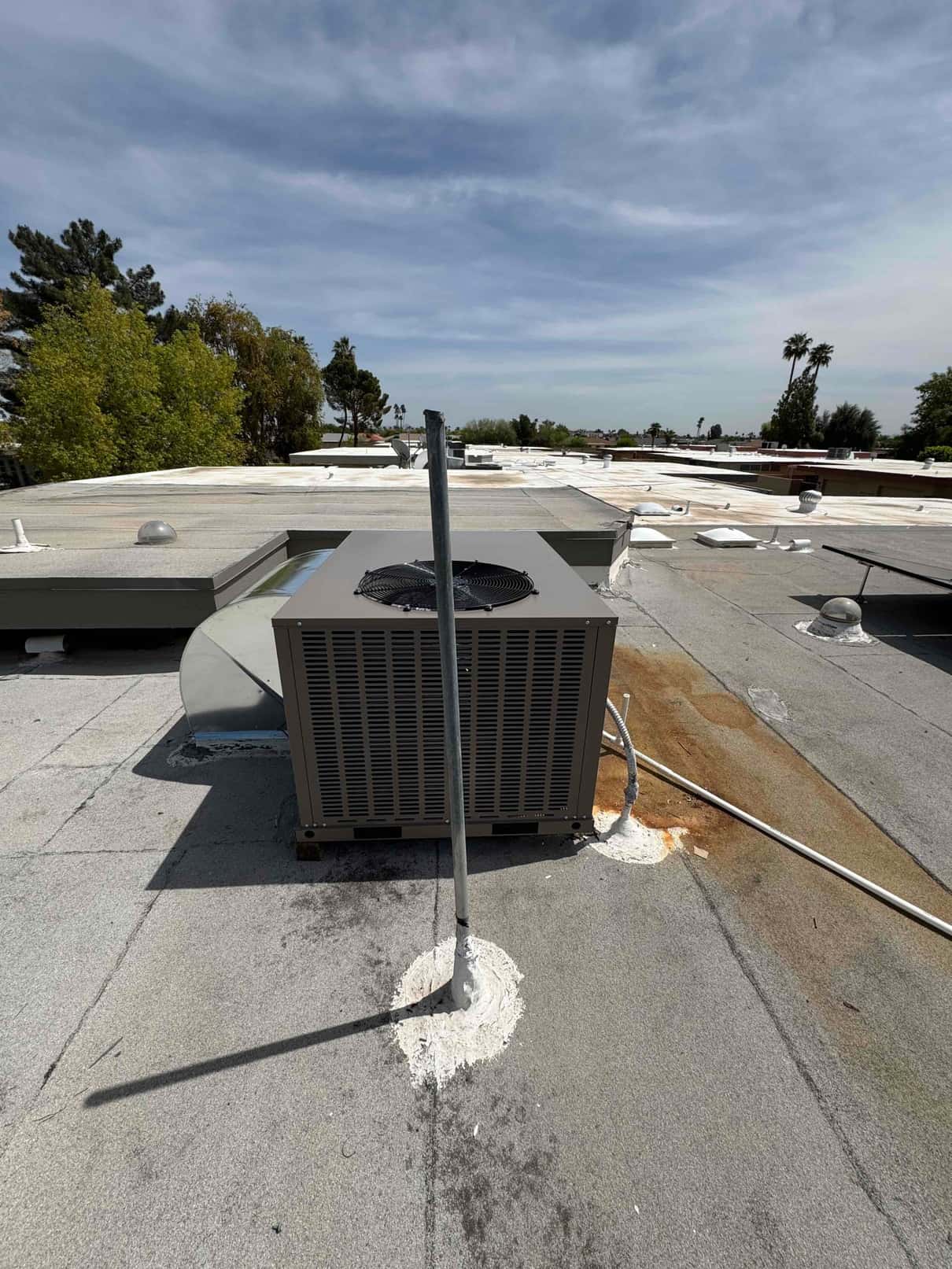 New rooftop packaged HVAC unit set on the roof with sealed penetrations and insulated refrigerant lines routed to the curb.