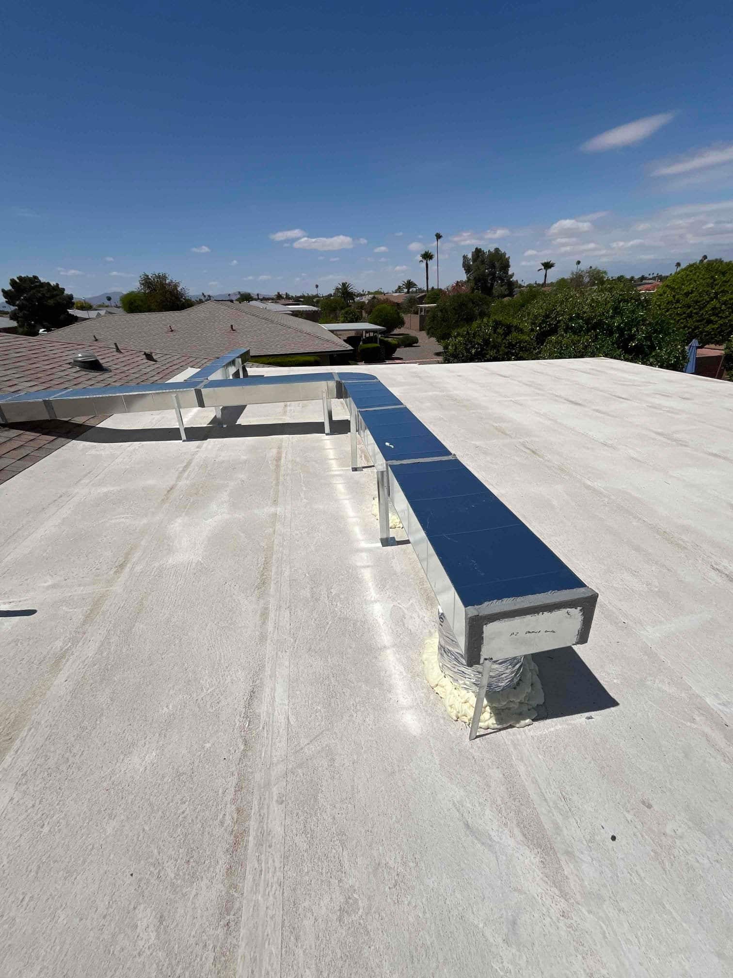 New rooftop rectangular metal duct run installed on standoffs with sealed roof penetration and mastic around the boot.