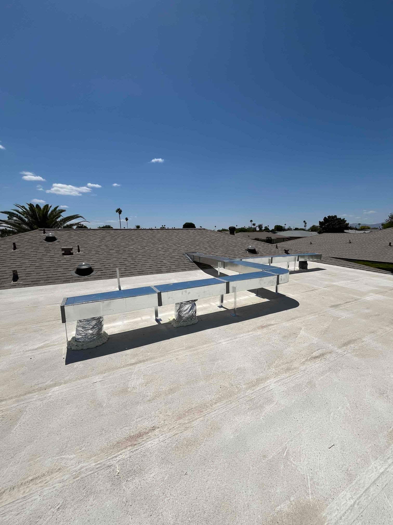 New rooftop sheet-metal duct runs on stands with sealed flex connections penetrating the roof membrane.