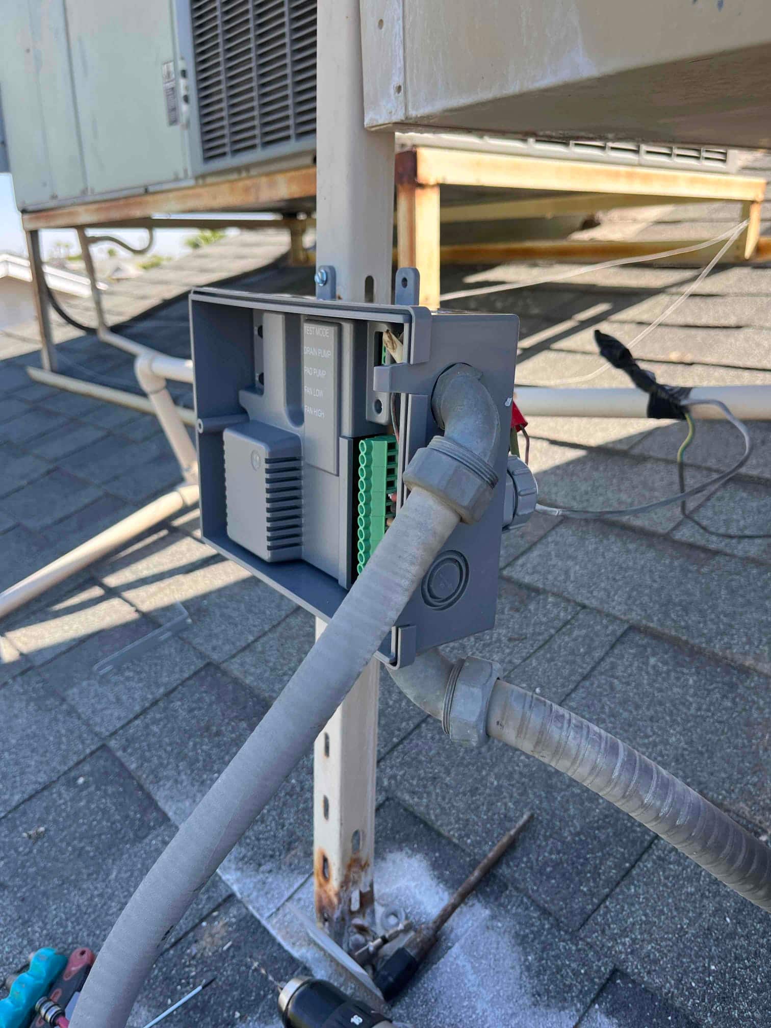 Open electrical junction box on rooftop HVAC unit showing conduit connections, wiring terminals, and exterior disconnect components during service.
