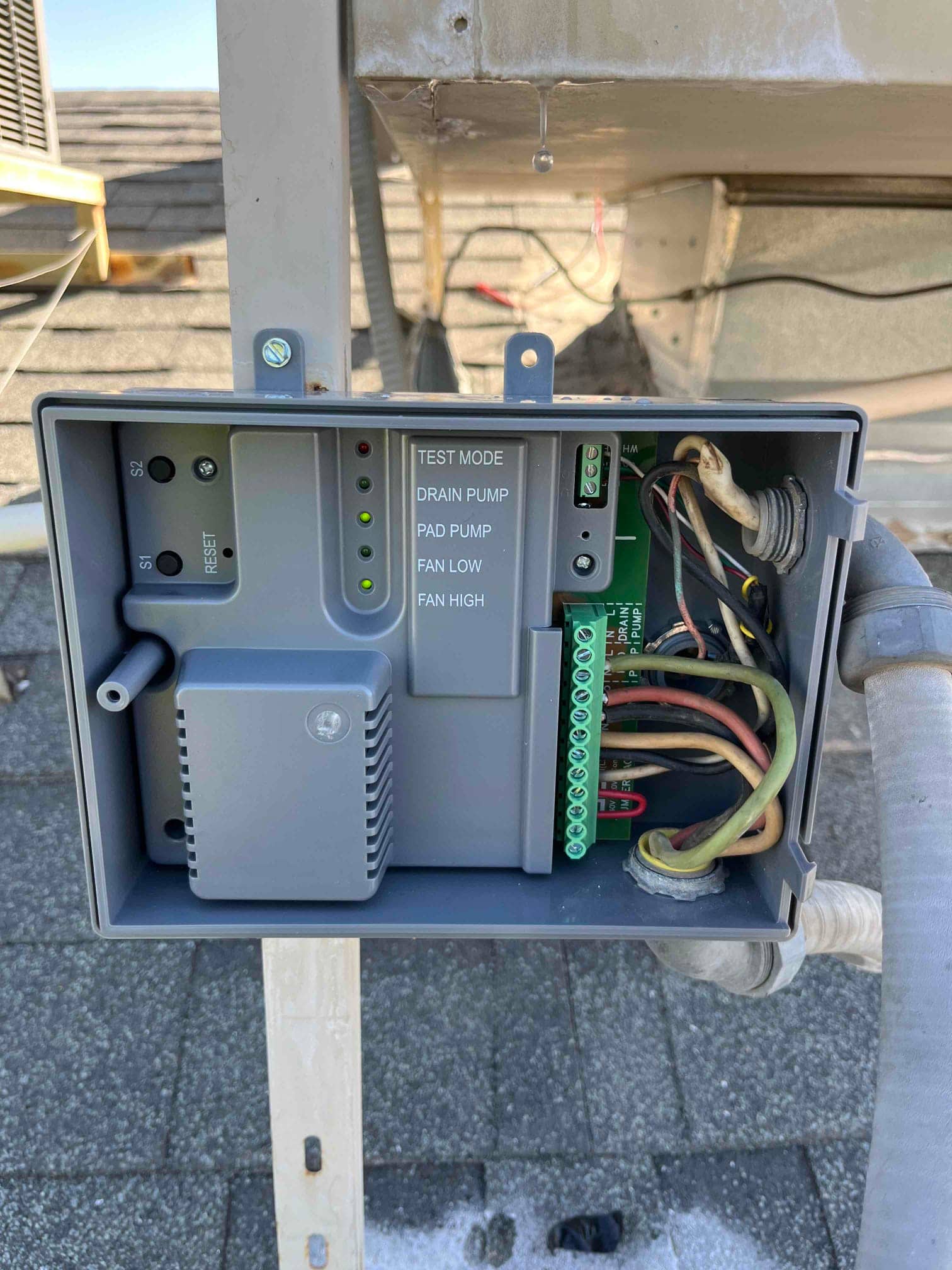 Open evaporative cooler control box showing wiring, terminal strip labeled for pump and fan speeds, and status LEDs.
