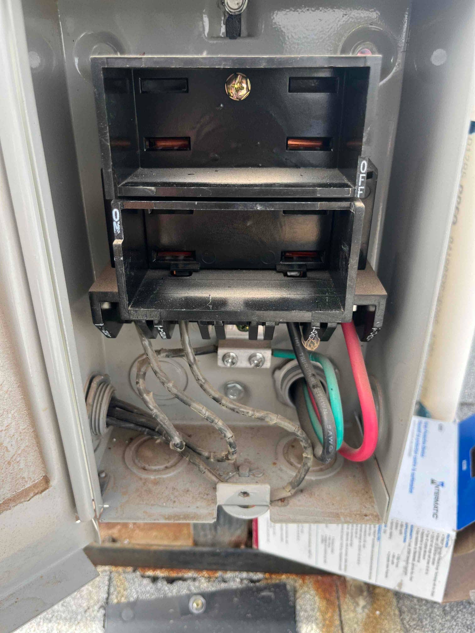 Outdoor AC disconnect with pull-out removed, showing line and load wiring, ground connection, and conduit entries.