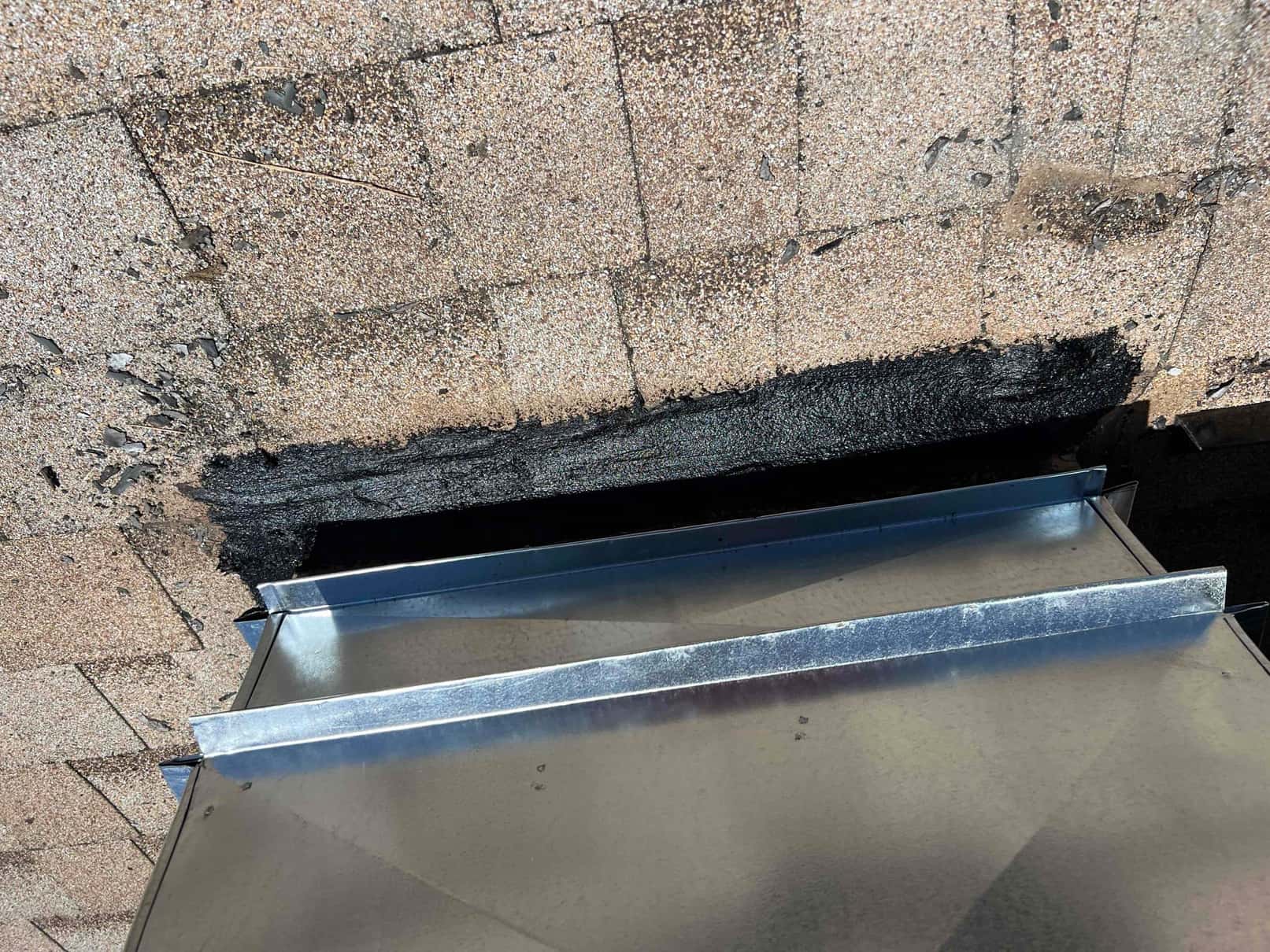 Roof penetration prepared with sealant and sheet metal curb in place for new HVAC duct or vent connection.