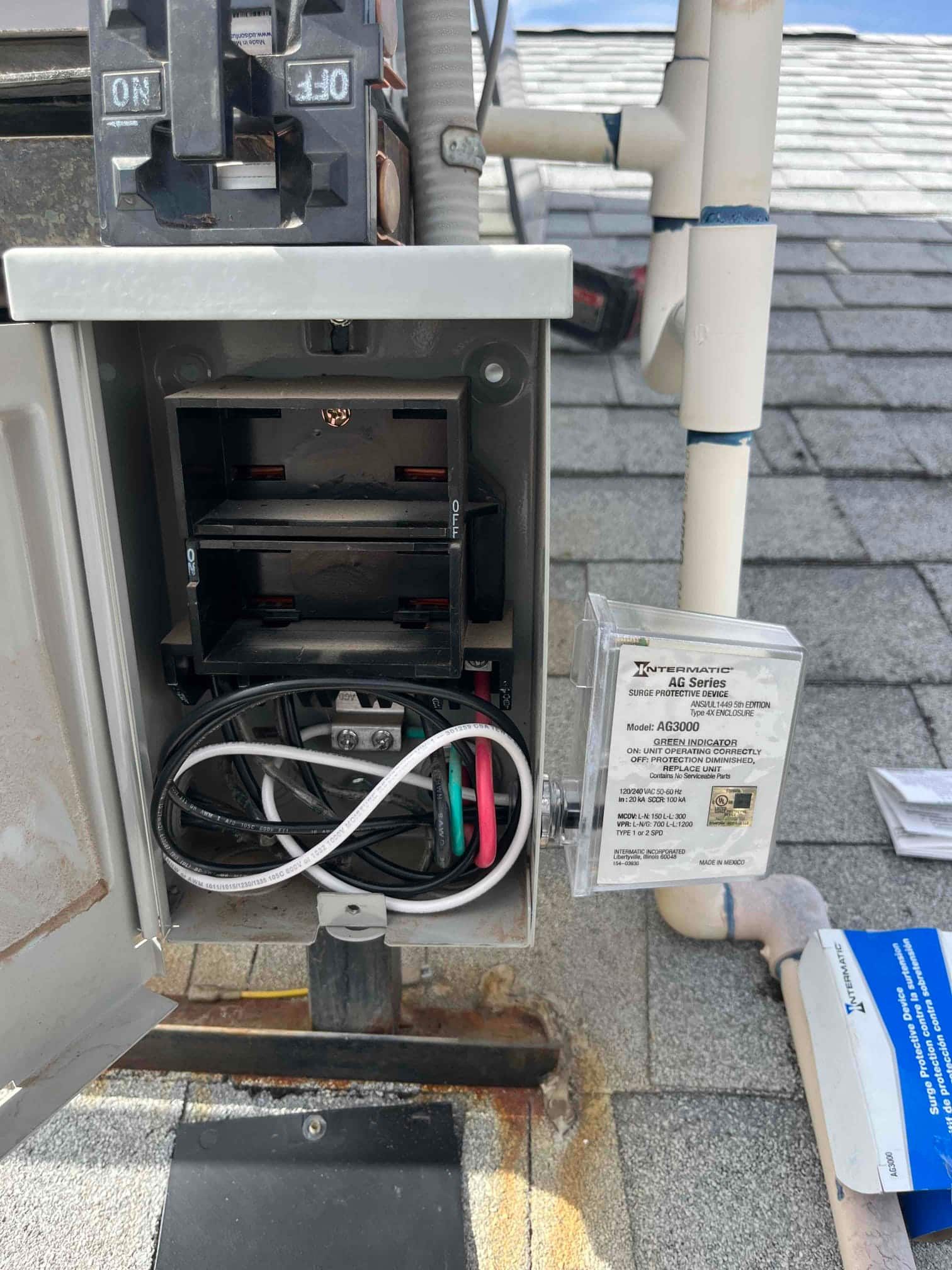 Surge protective device installed in an outdoor disconnect box, showing connected line and neutral wires with cover open.
