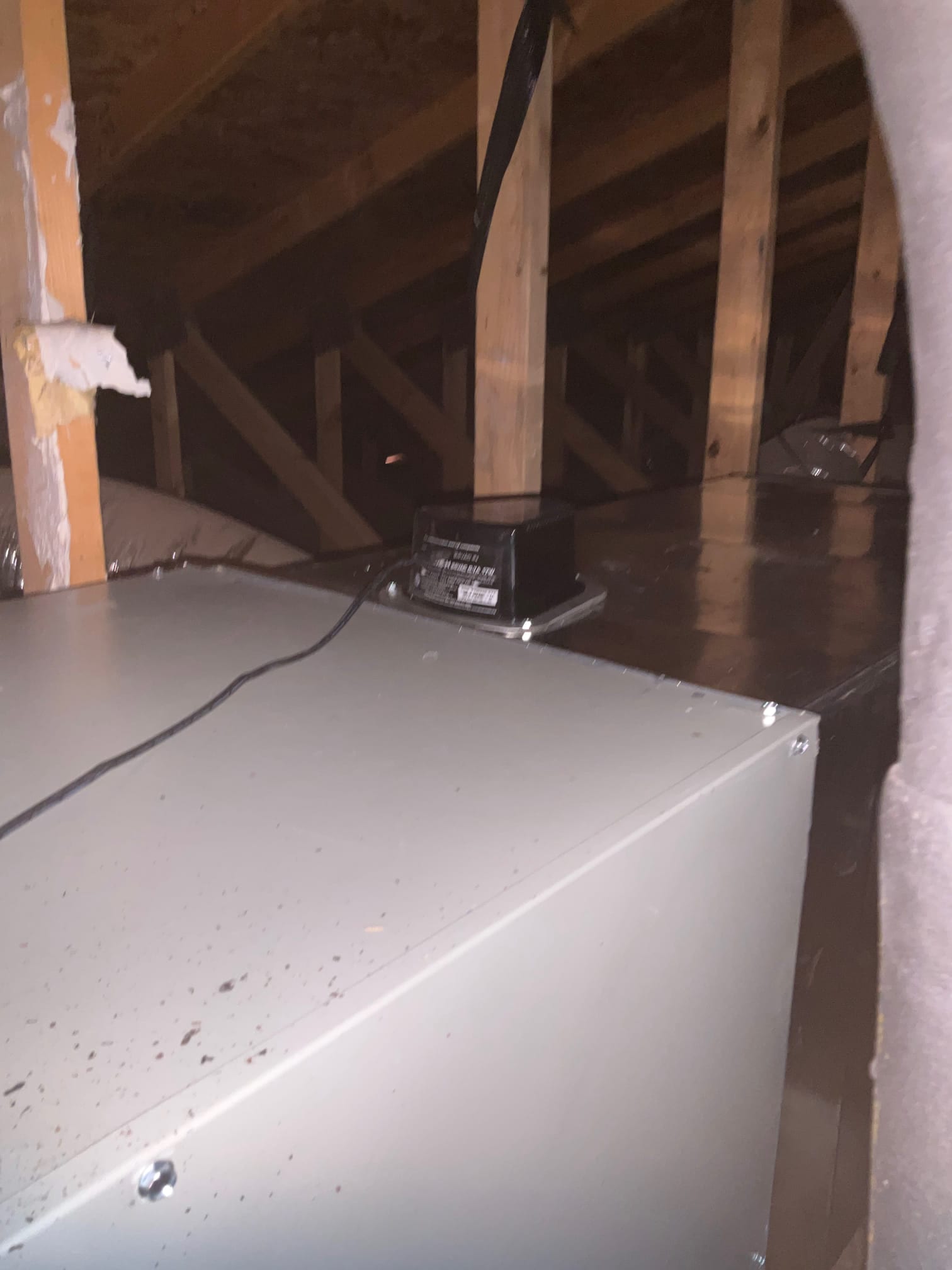 Air handler and duct transition installed in attic space with support strapping and sealed sheet metal connections visible.