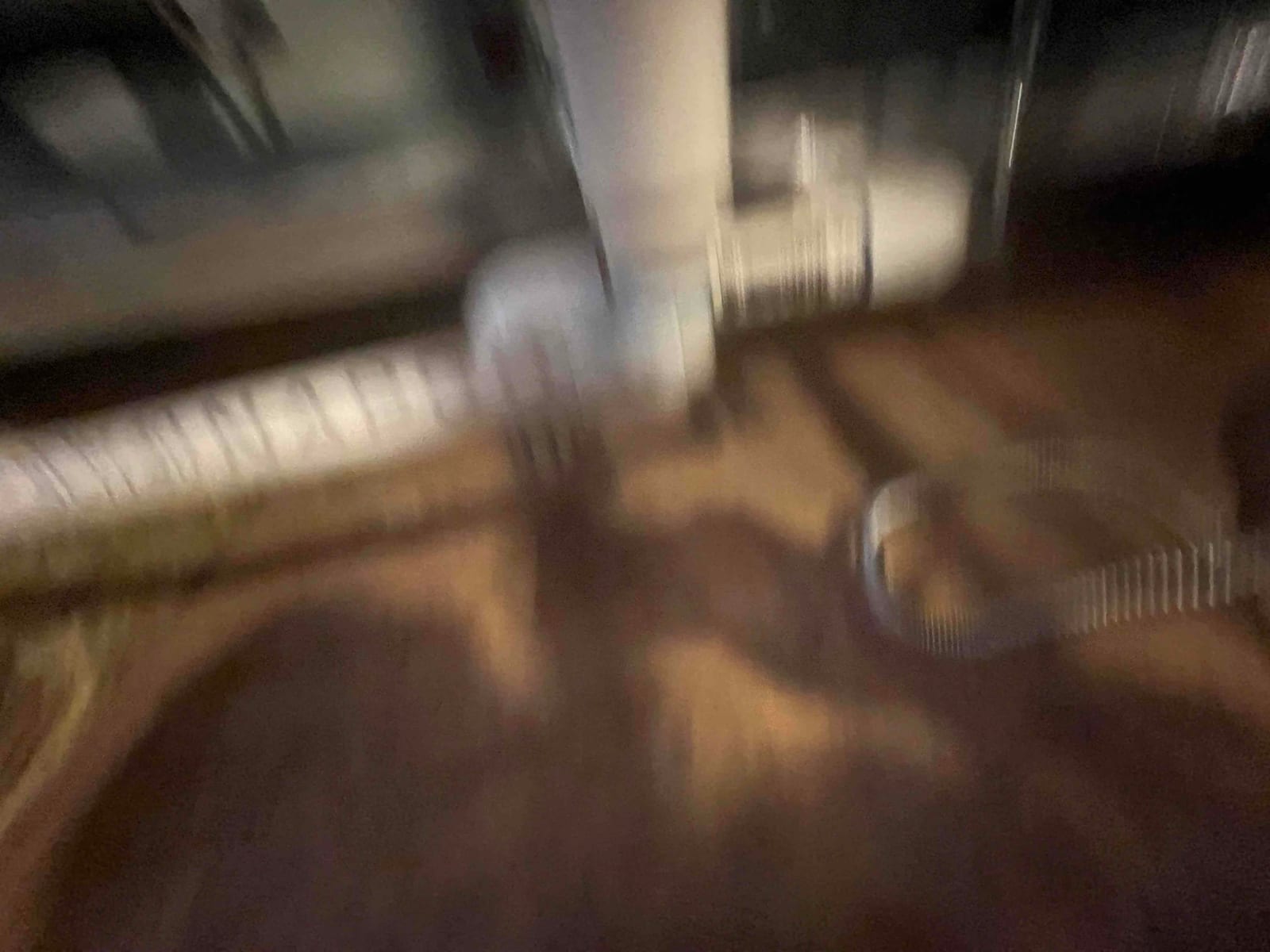 Blurry view of PVC condensate drain piping and flexible conduit on the attic floor beside the air handler.