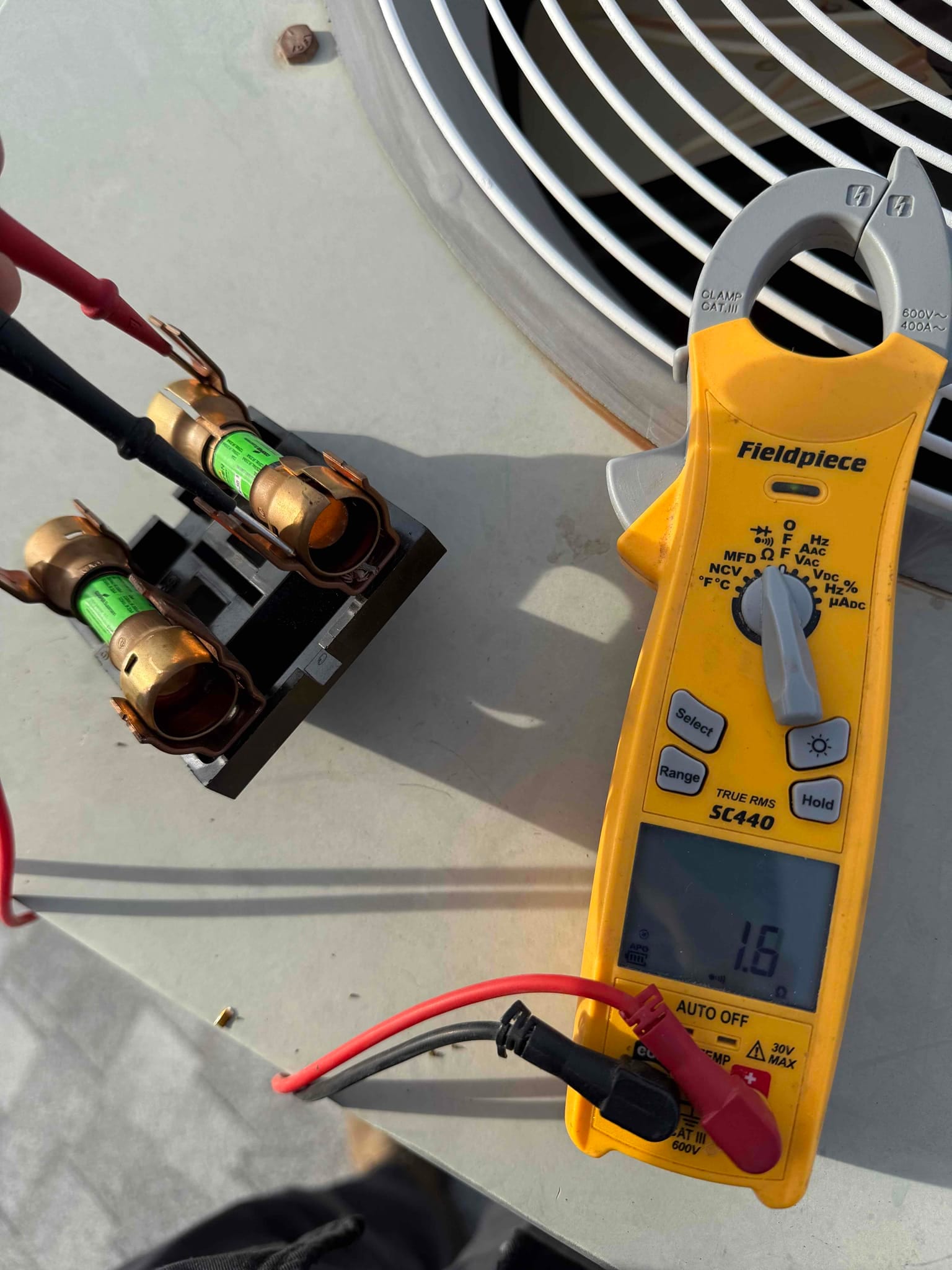 Clamp meter shows 1.6 A while measuring current across the time-delay fuse assembly at the disconnect.