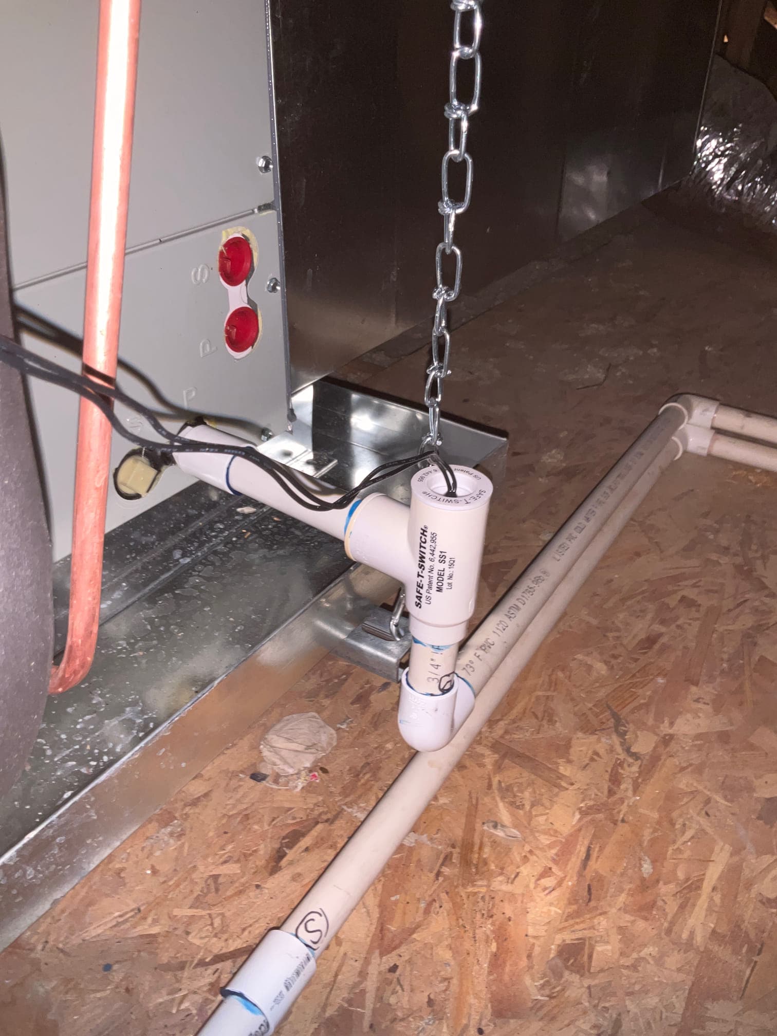 Condensate drain assembly with float safety switch installed at the air handler, connected to PVC piping on the attic deck.