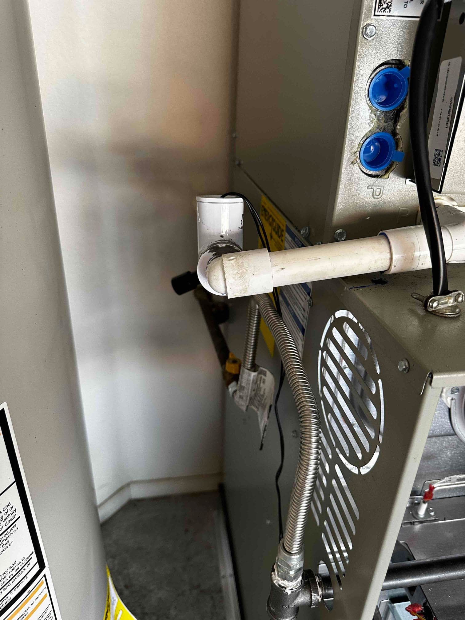 Condensate drain with cleanout tee and trap connected to the new air handler, alongside gas flex connector and vented panel.