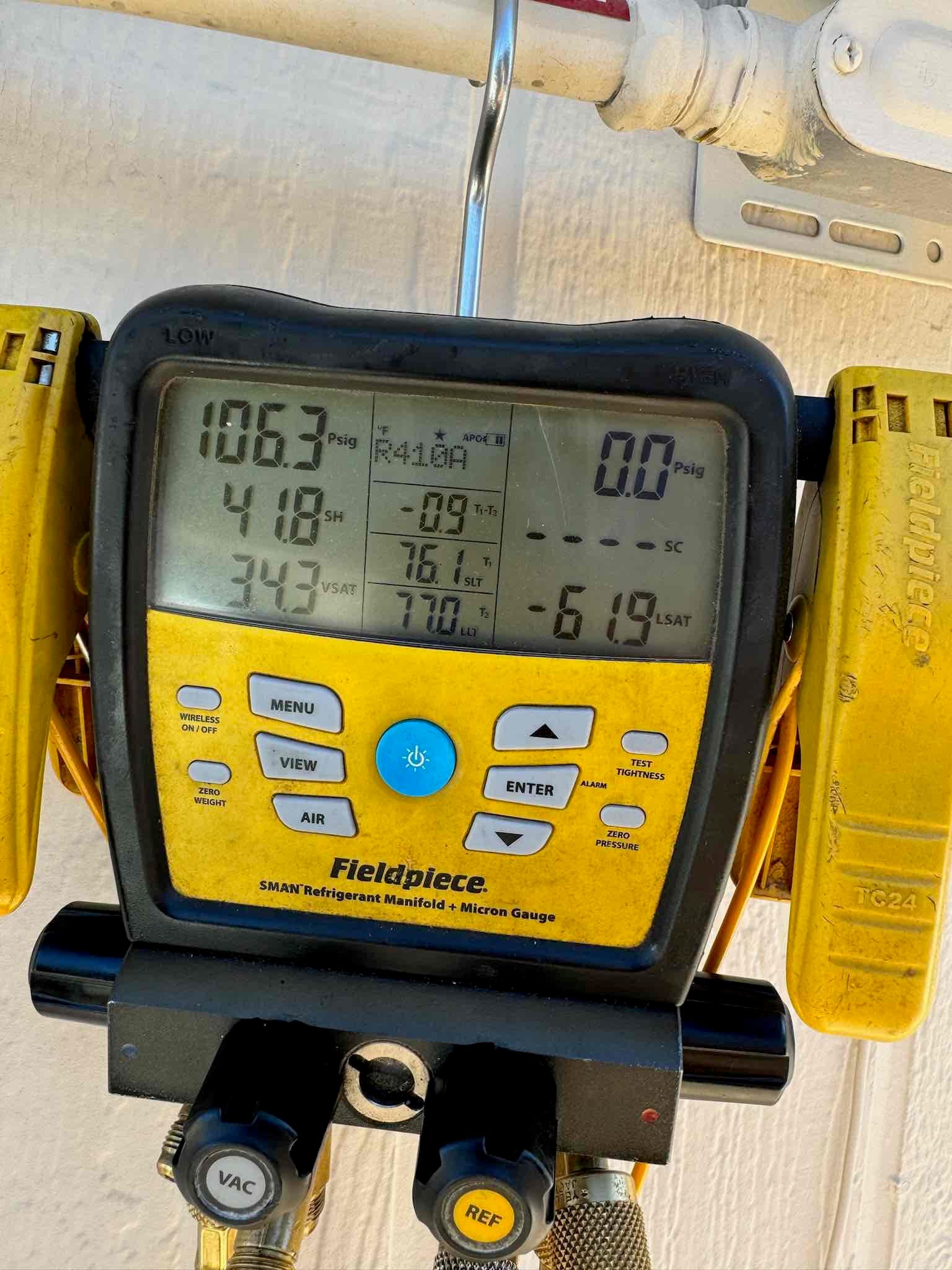 Digital manifold on the new system shows operating pressures with R‑410A selected, documenting suction and liquid pressures during commissioning.