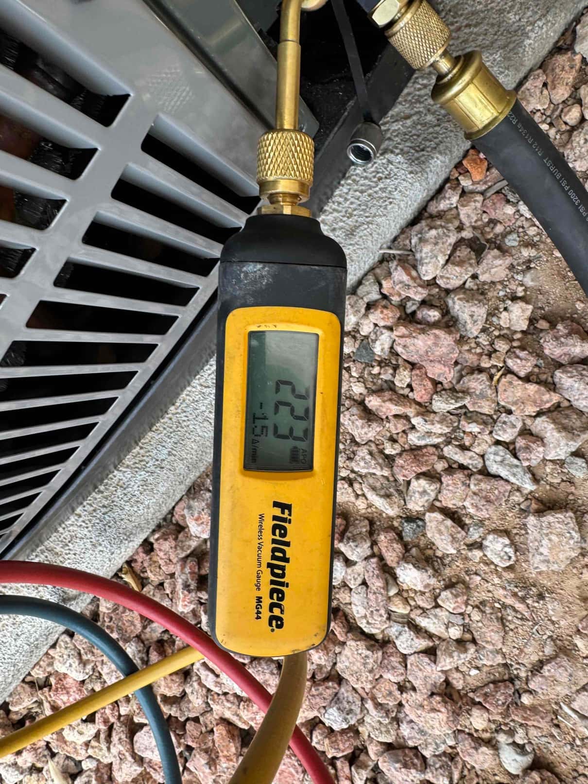 Digital micron gauge connected at the outdoor unit shows 223 microns during evacuation before releasing refrigerant charge.