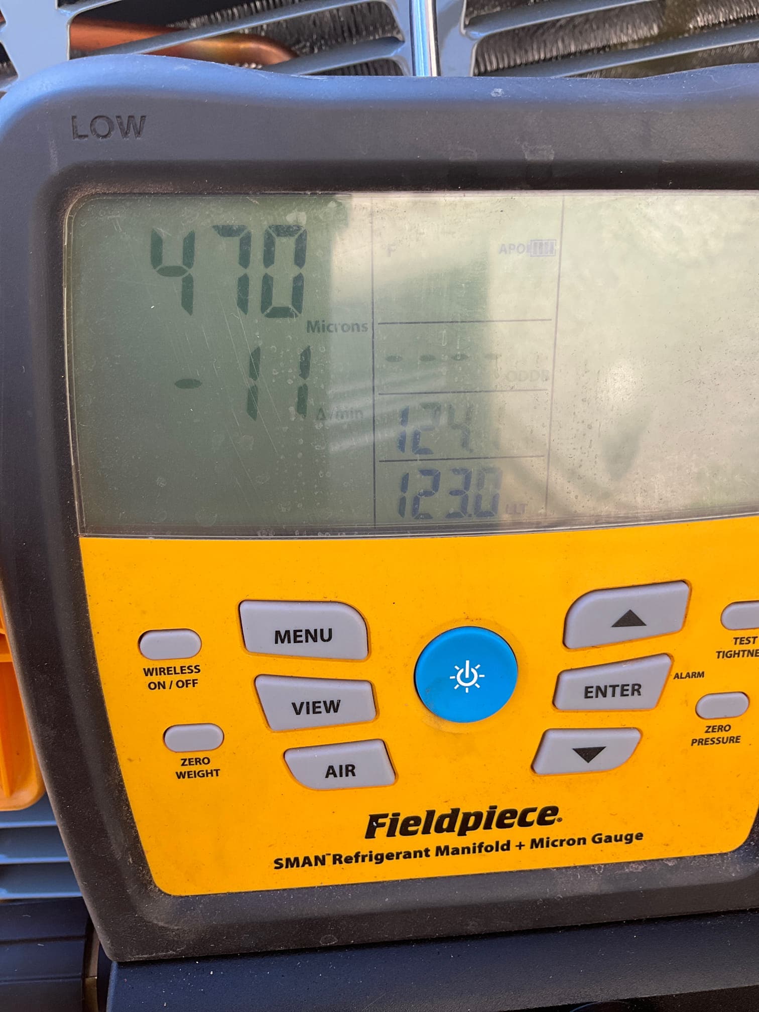 Digital micron gauge on the manifold shows 470 microns, confirming a deep vacuum during system evacuation before refrigerant charging.