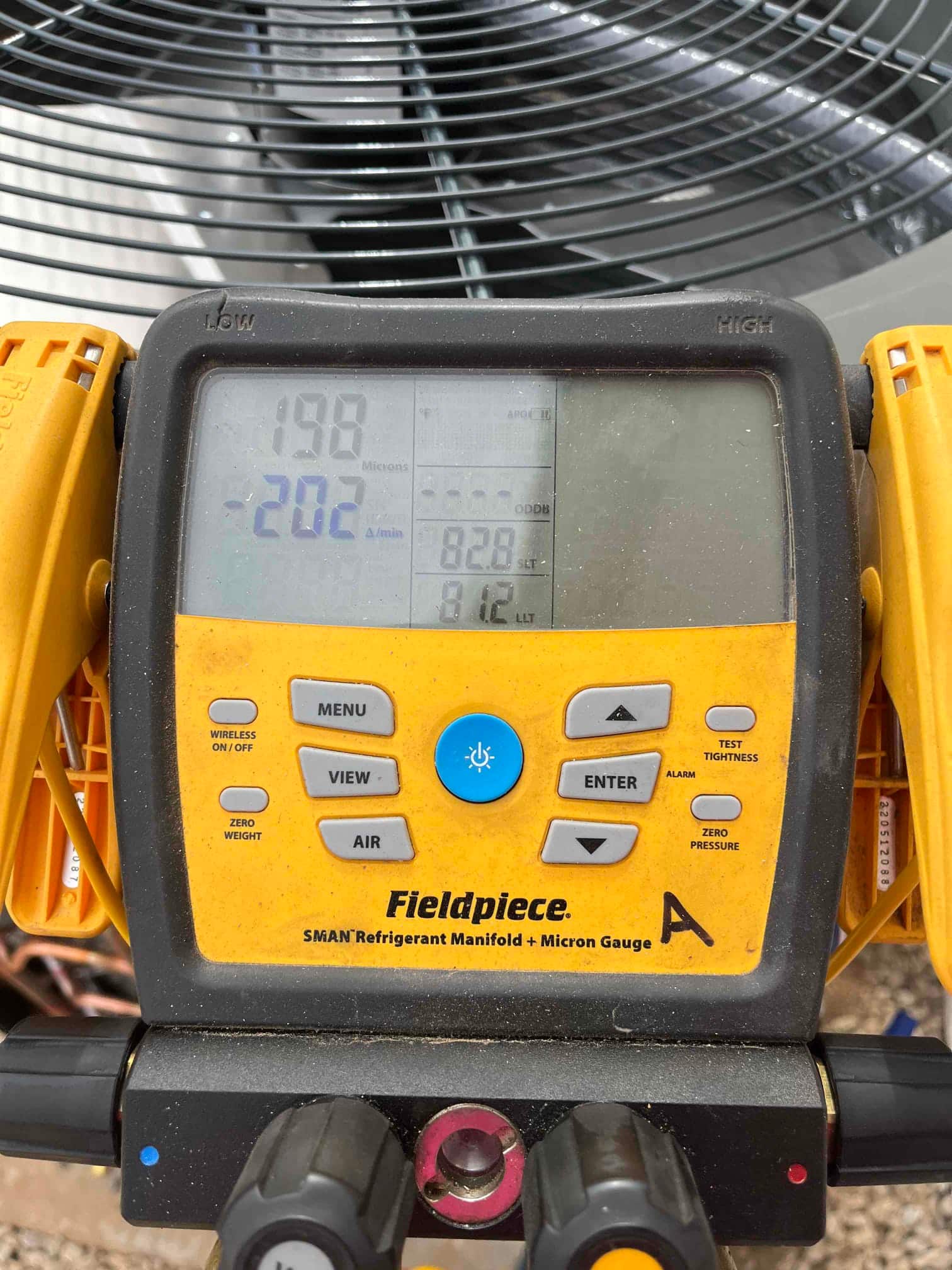 Digital micron gauge on the refrigerant manifold shows 198 microns during system evacuation prior to charging.