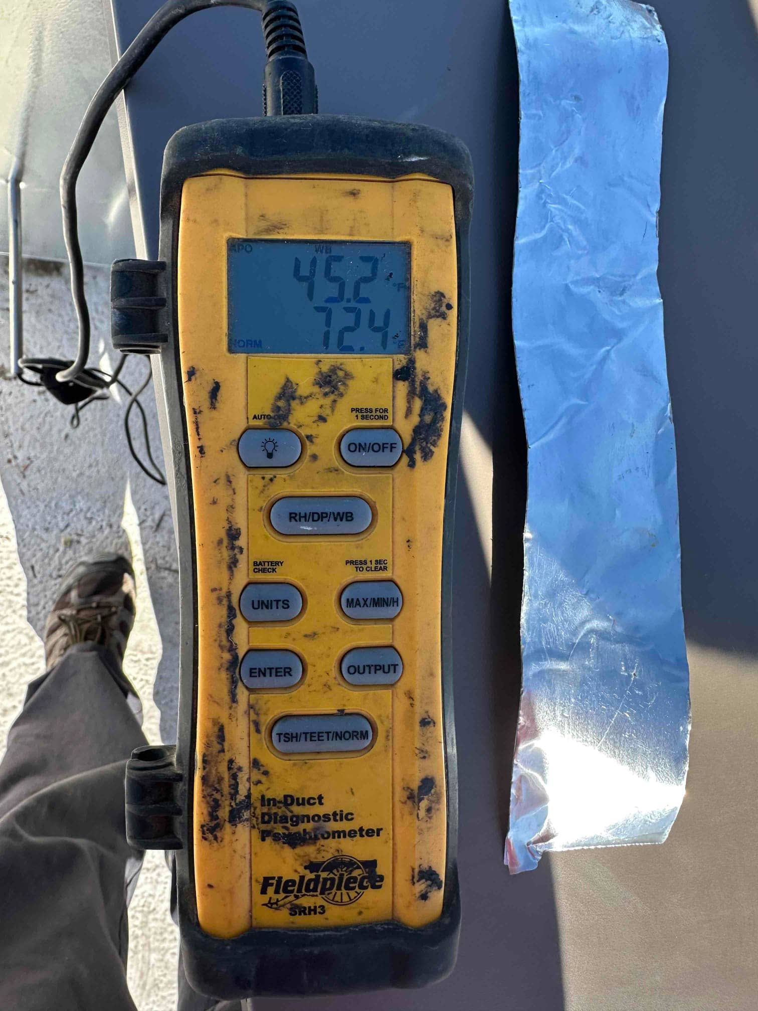 Digital thermometer displays 45.2 degrees and 72.4 degrees during duct temperature checks to document supply and return air conditions.