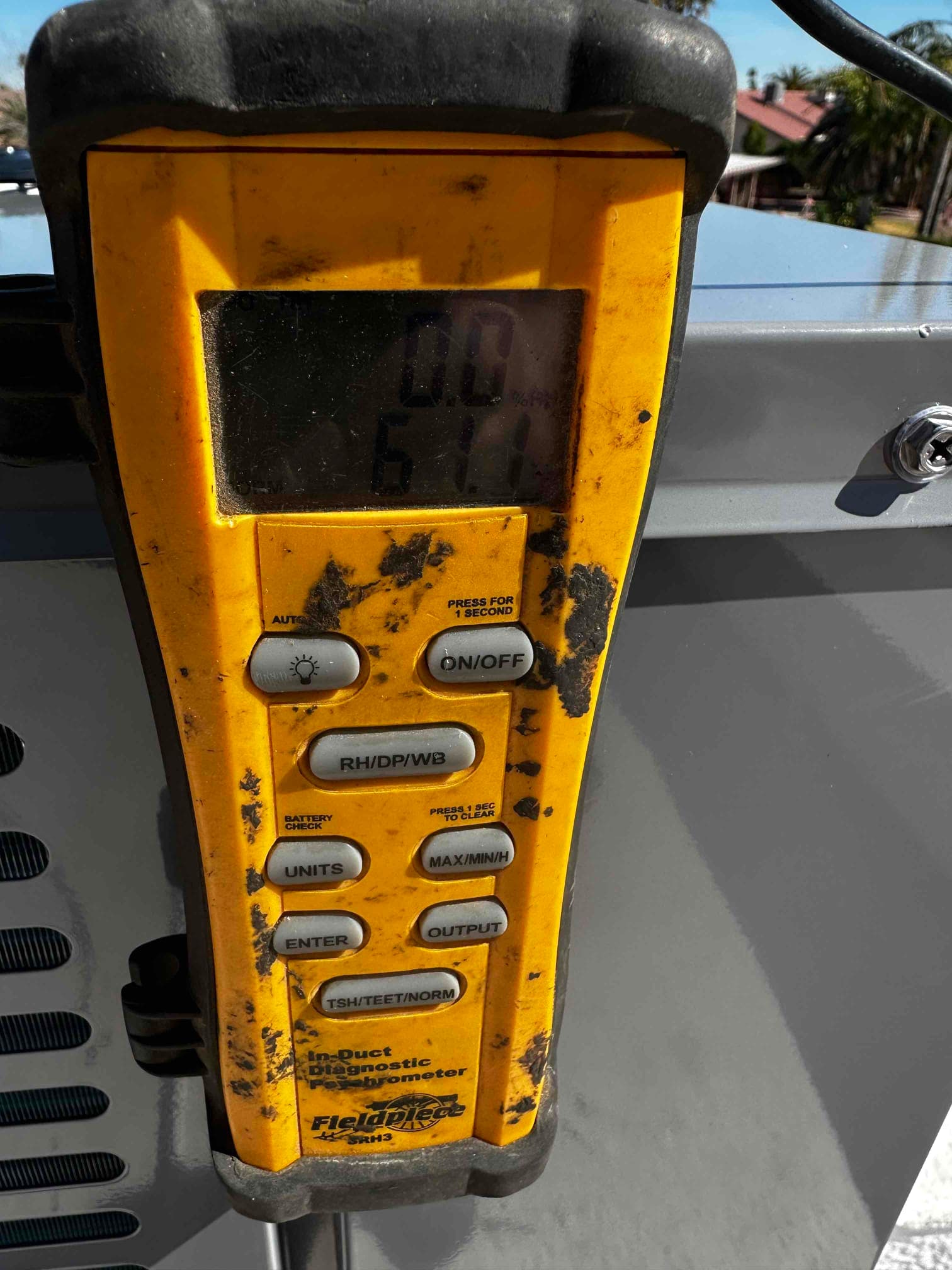 Digital thermometer displays 61°F during air temperature measurement as part of system commissioning.