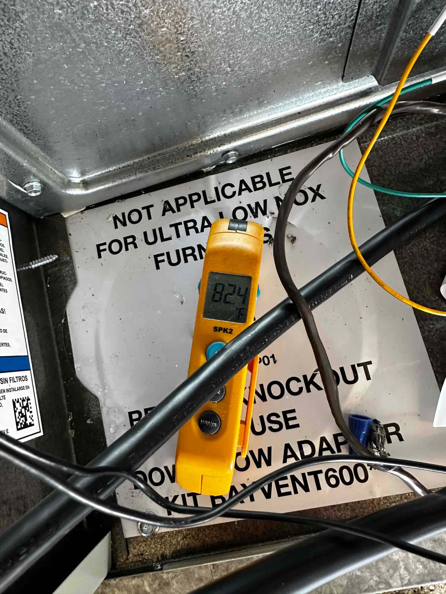 Digital thermometer probe reads 82.4 degrees Fahrenheit while measuring air temperature inside the indoor unit cabinet.