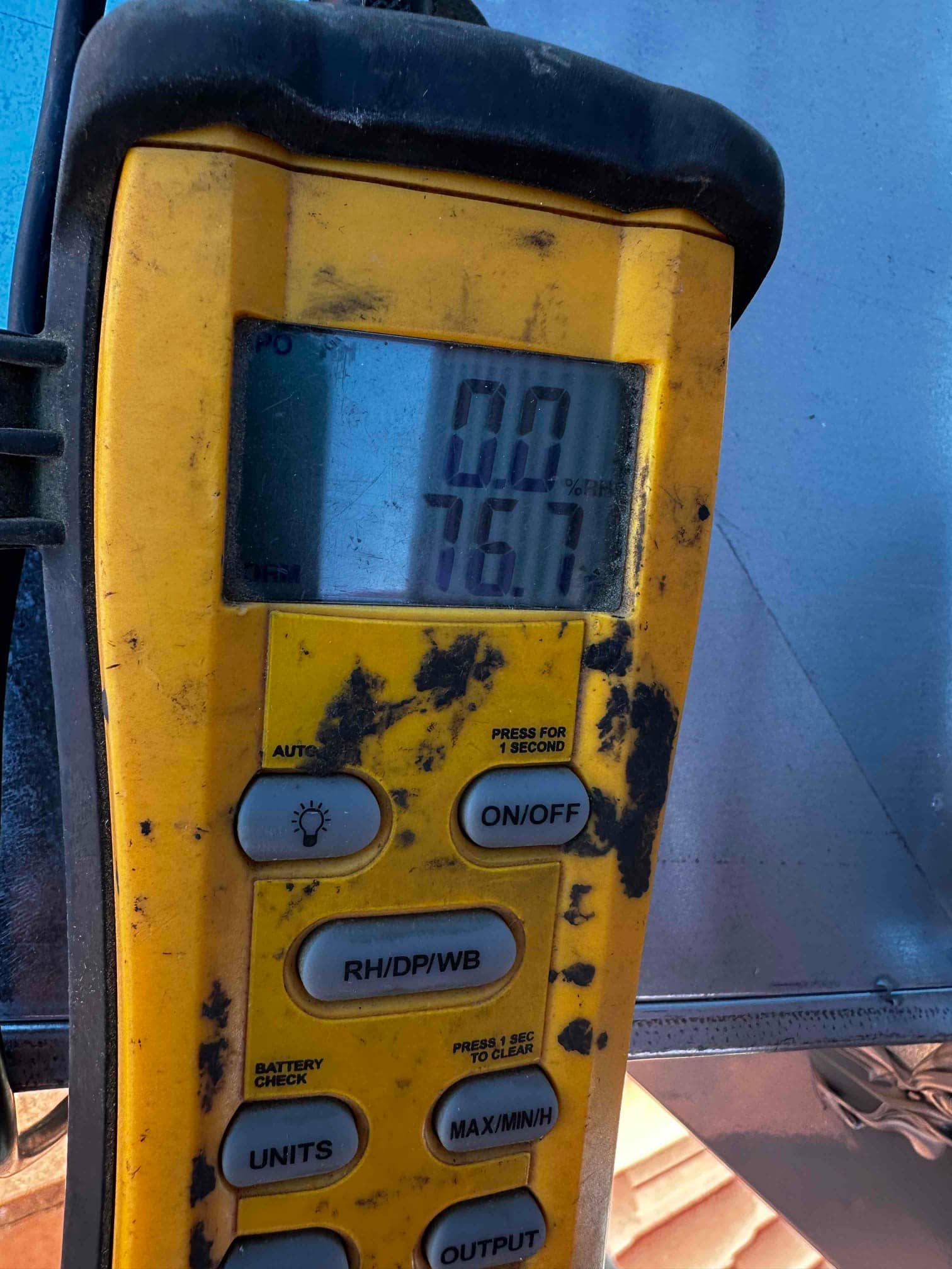 Digital thermometer shows 76.7 degrees Fahrenheit while checking air temperature during HVAC commissioning.
