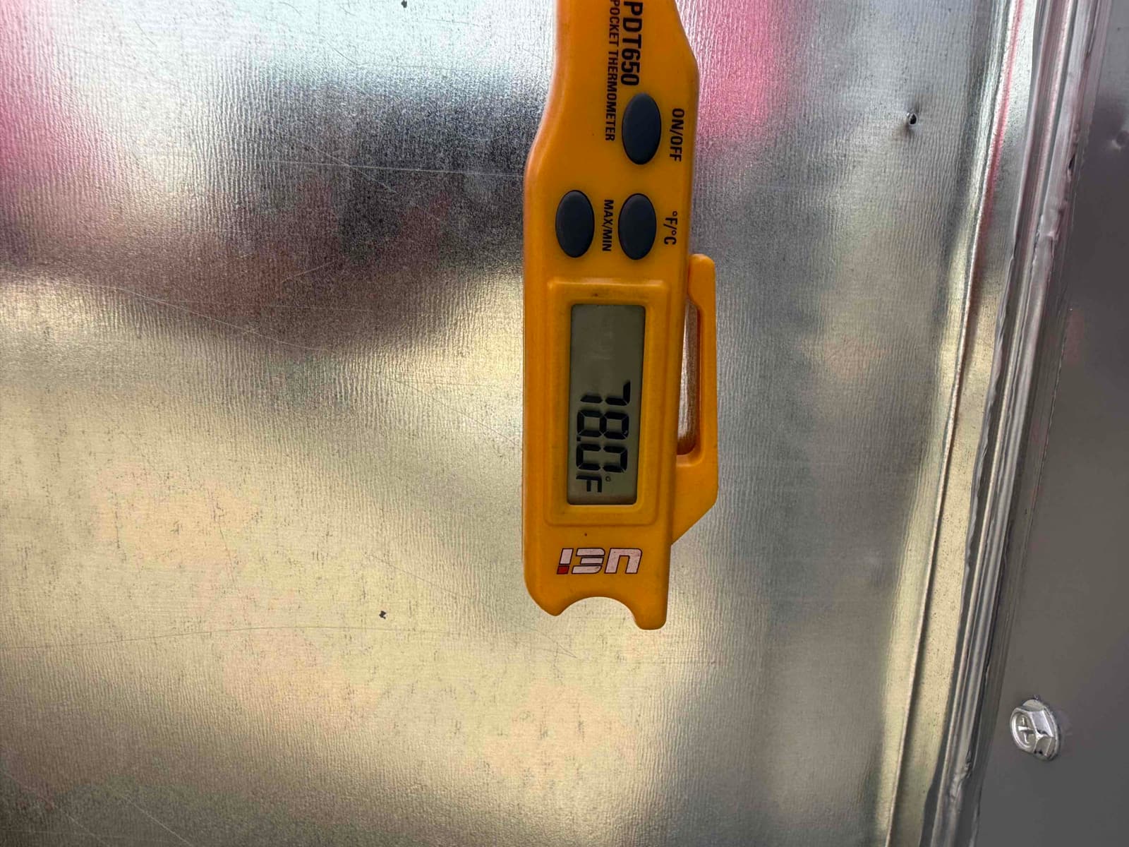Digital thermometer shows 78.0°F during a return air temperature check on the metal duct surface.